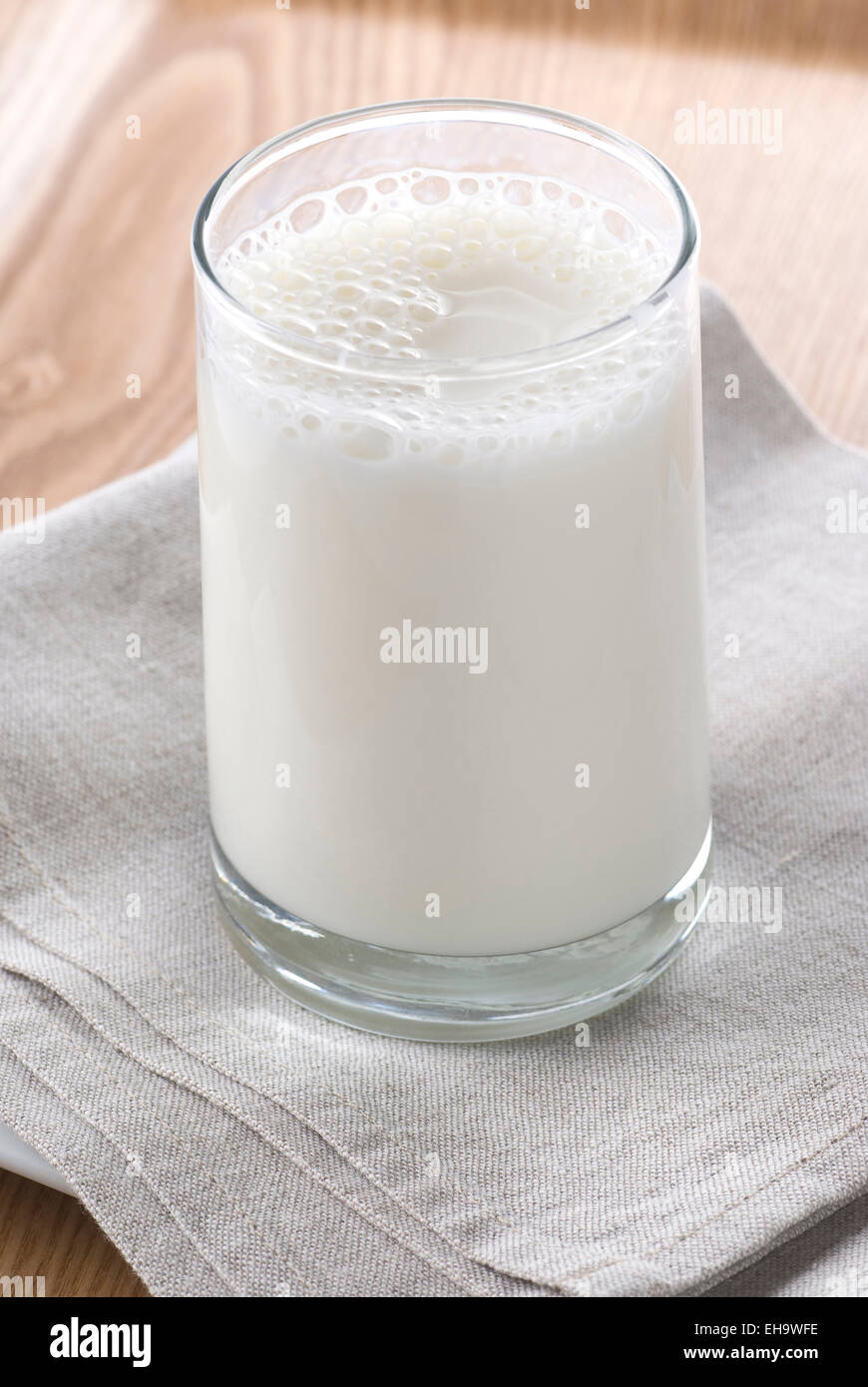 A glass of milk on a table linen napkin, plate and a tray. Stock Photo