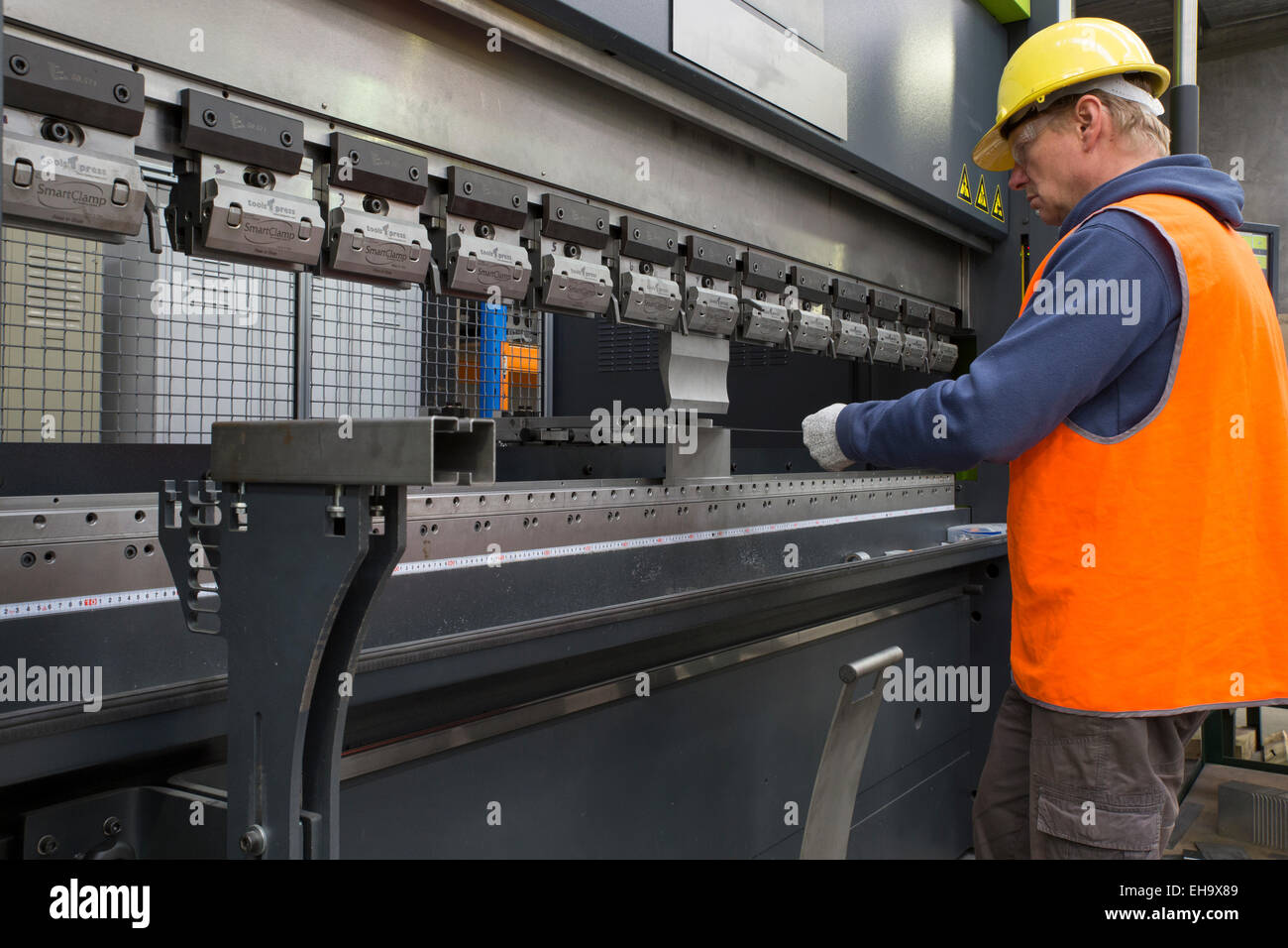 Metal industry worker operates CNC brake press machine Stock Photo - Alamy