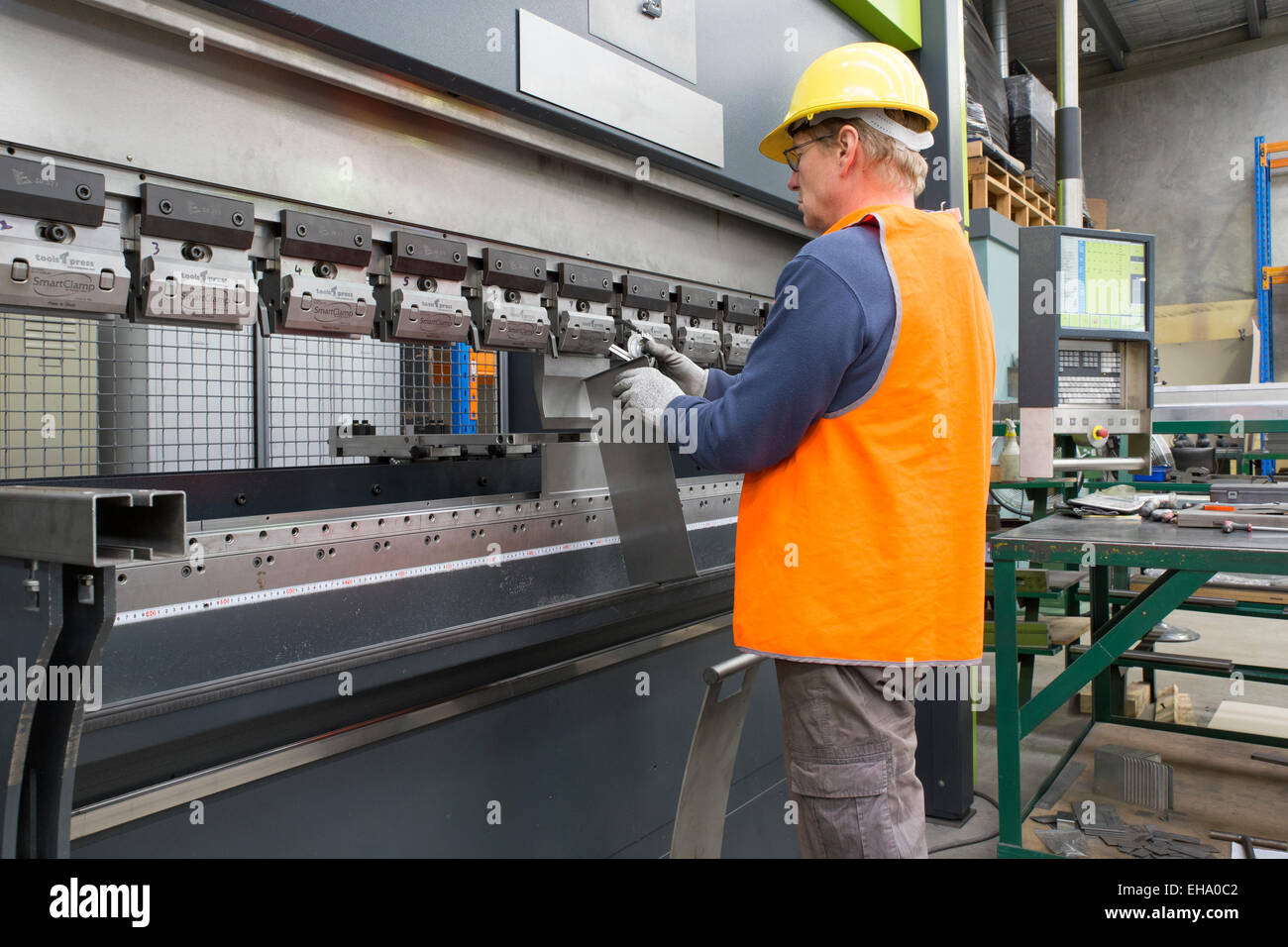 metal industry worker checks angle on folded sheet metal part. Stock Photo