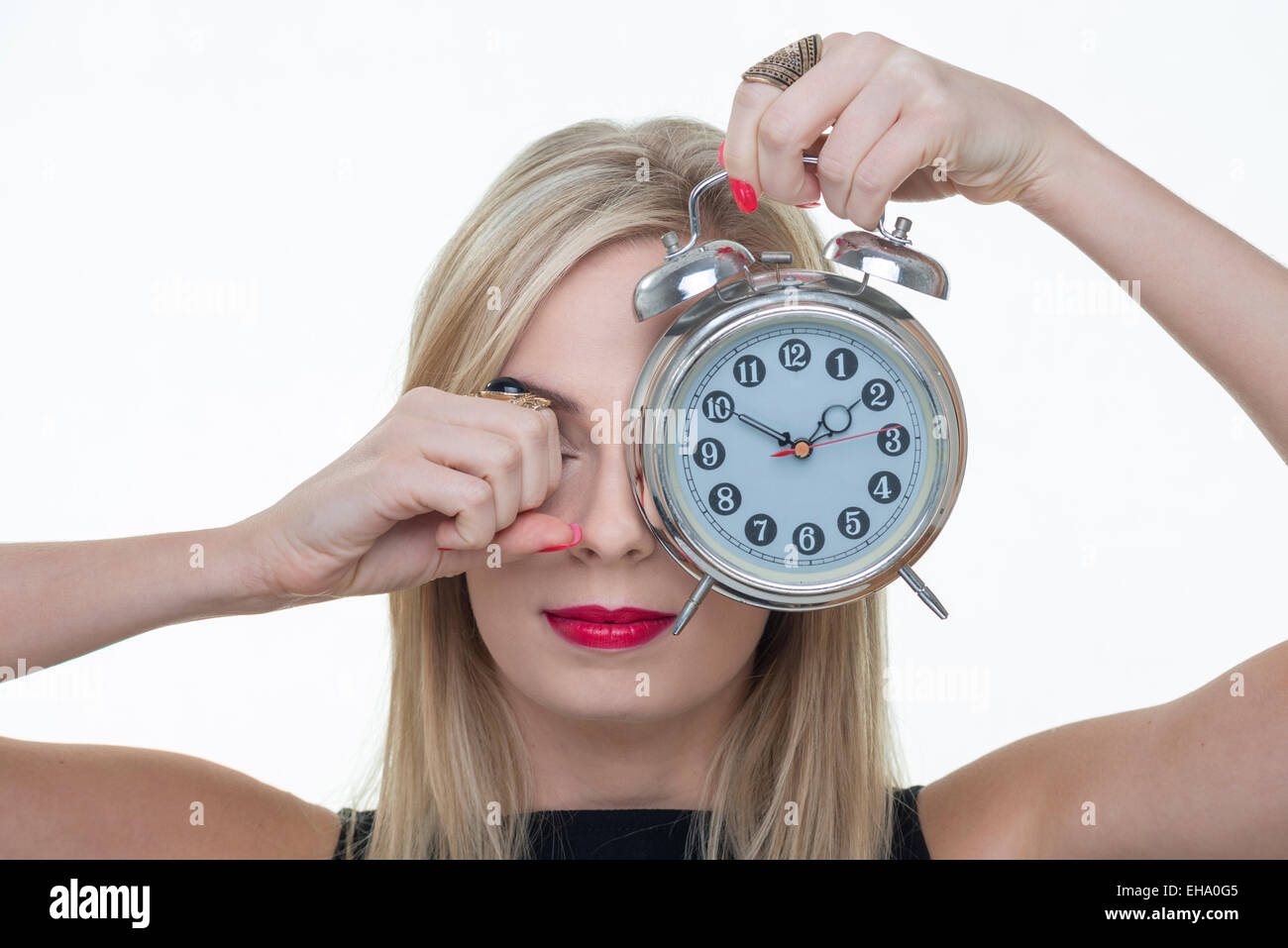 woman rubbing her eye holding an alarm clock Stock Photo