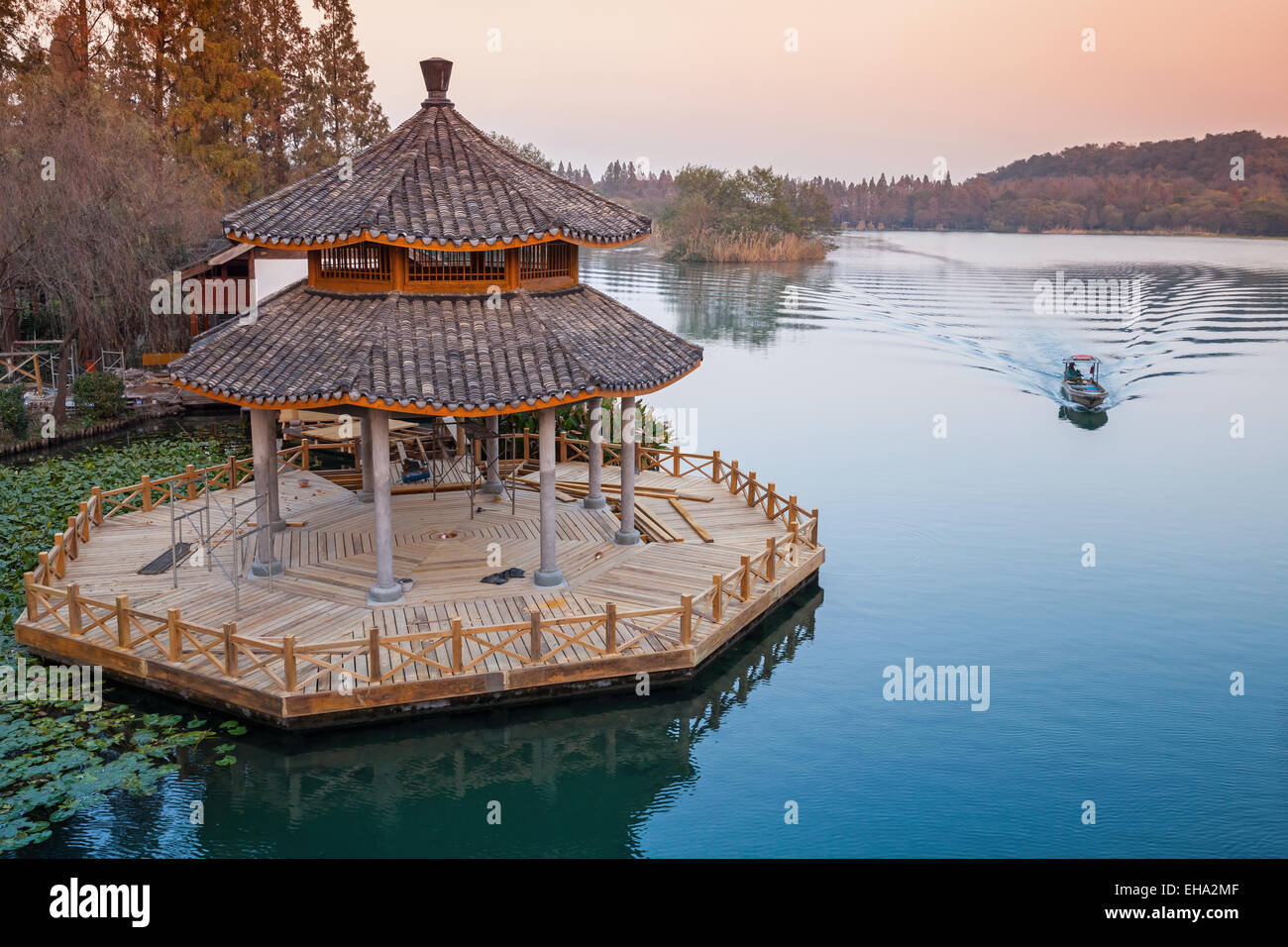 Small boat and round traditional Chinese wooden gazebo on the coast of West Lake park in Hangzhou city, China Stock Photo