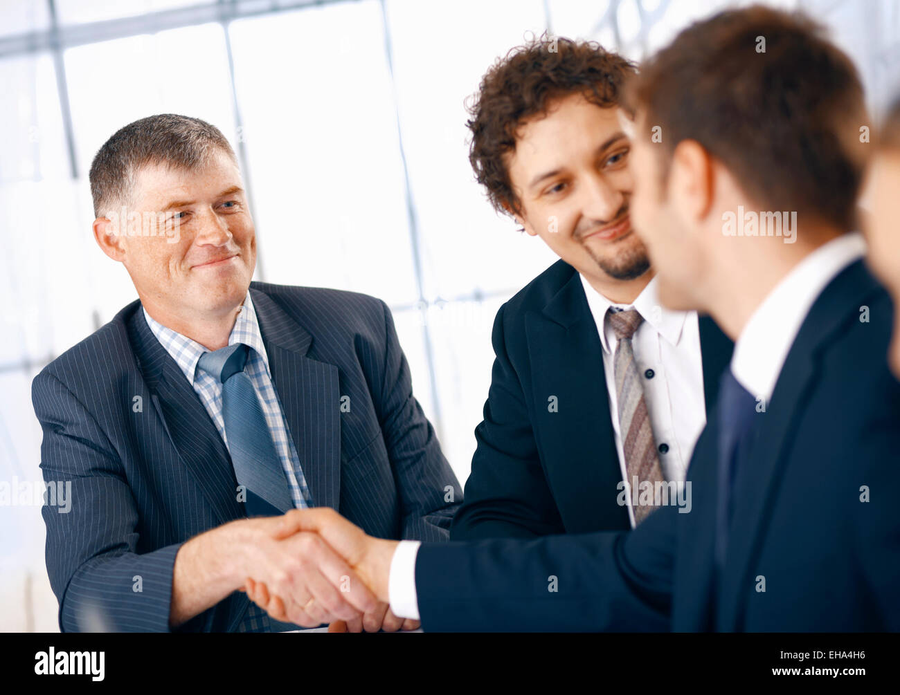 Business people shaking hands, coming to an agreement in the office. Stock Photo