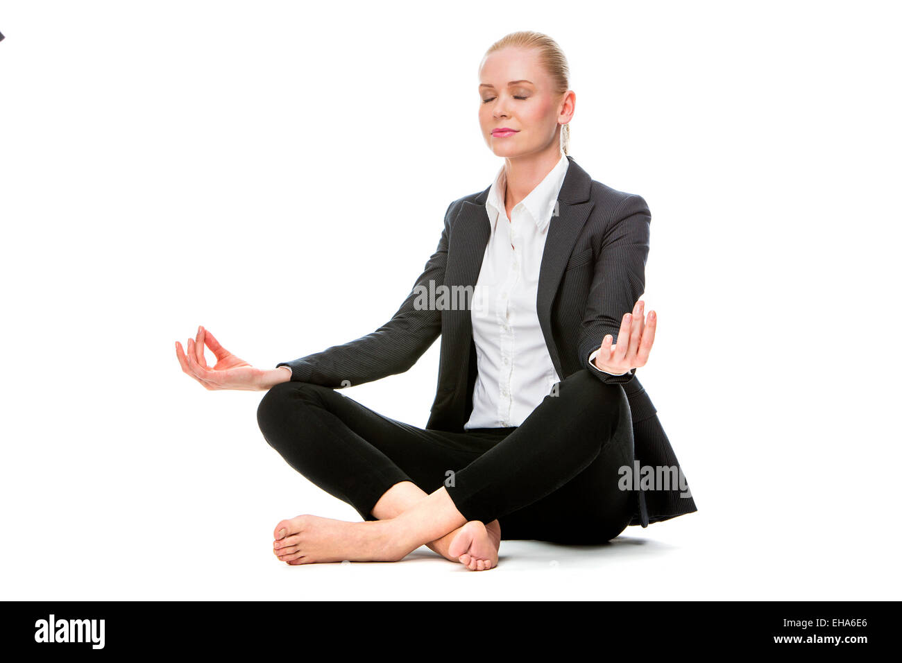 businesswoman seated on the floor doing a yoga position with her eyes closed Stock Photo