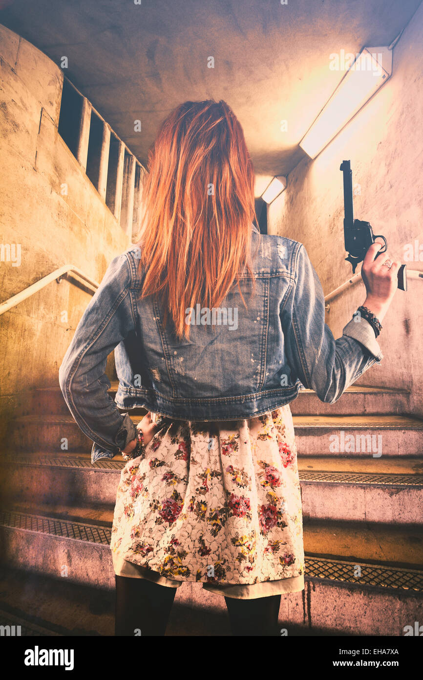 Rear view of a redhead woman on a gun at the entrance of a subway Stock Photo