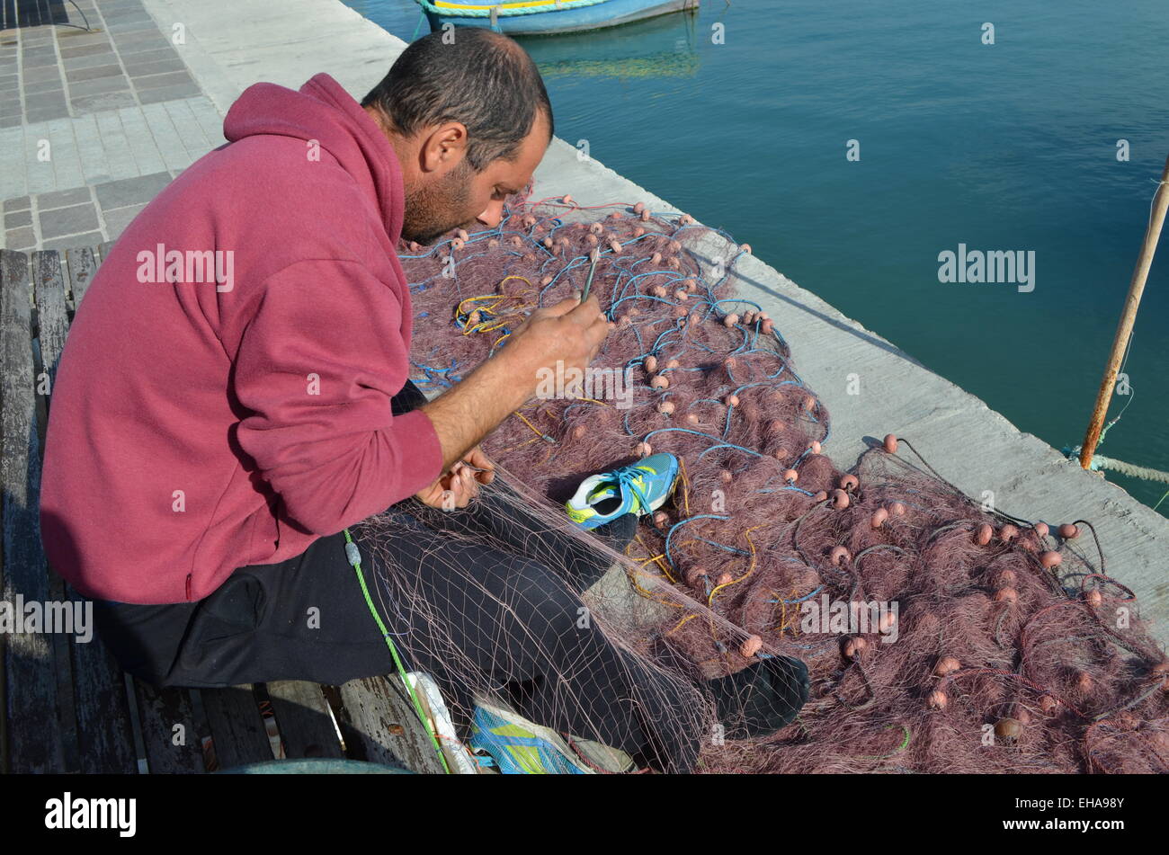 Malta,Marsaxlokk(pro.marsa-shlock)is a pretty little fishing village just south ofValletta. One ofthe fishermen mending his nets Stock Photo