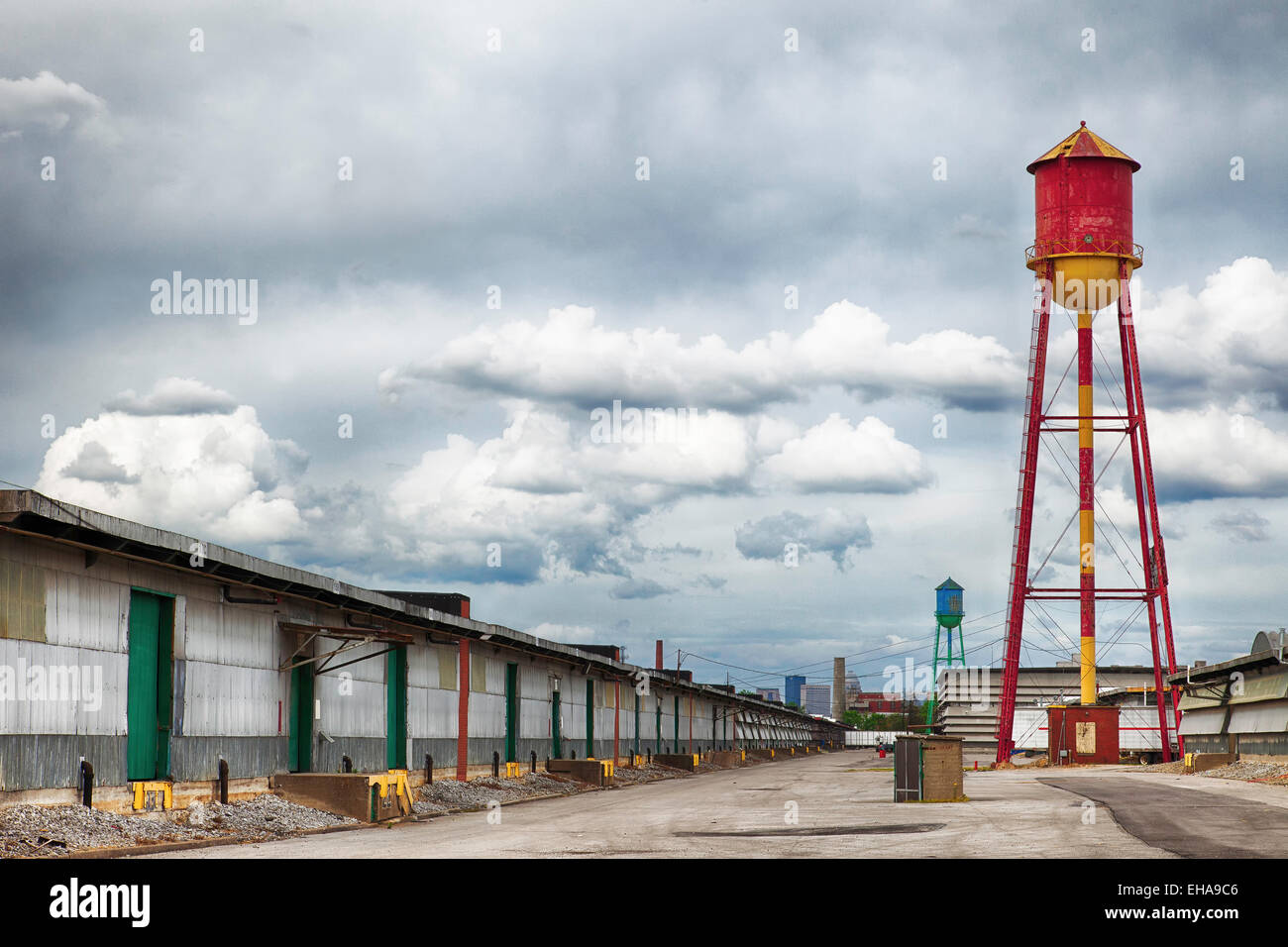 Two water towers in an abandoned warehouse district with garages and clouds in the sky. Stock Photo