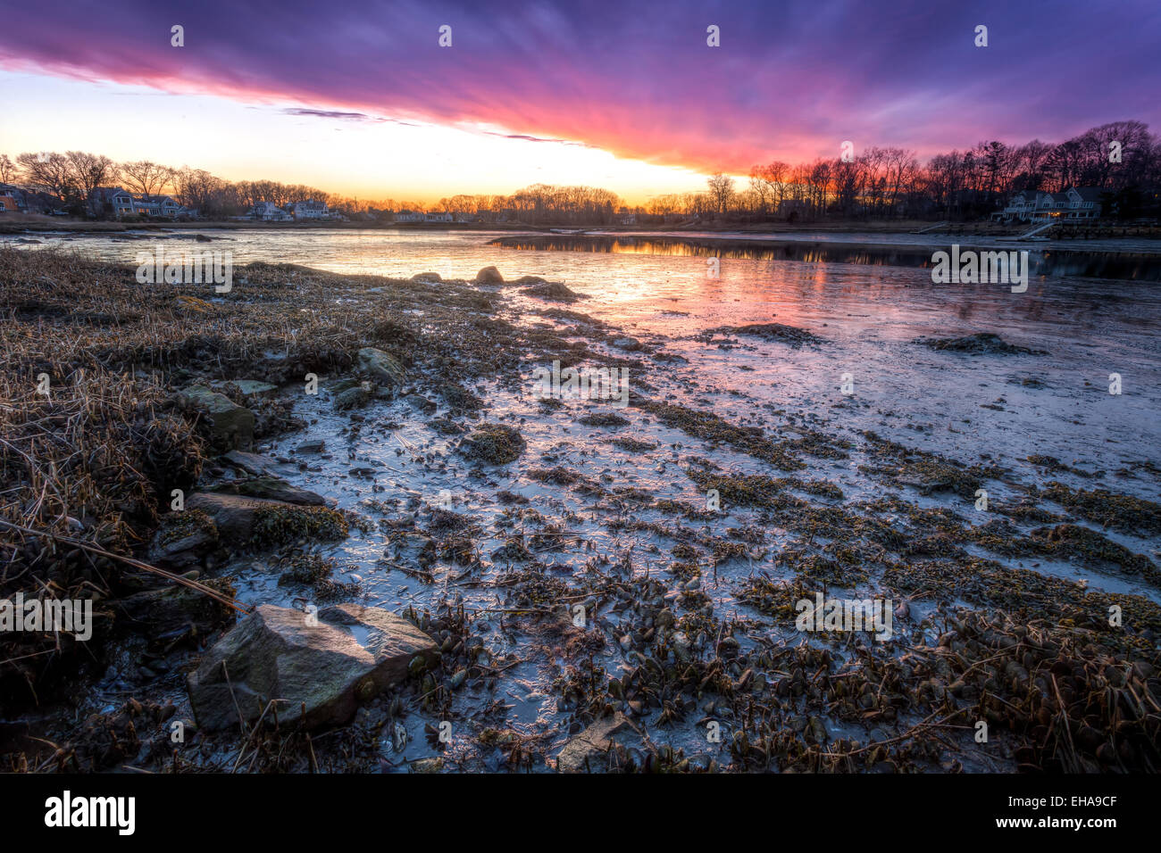 A color pink and purple sunset over a muddy waters at low tide. Stock Photo