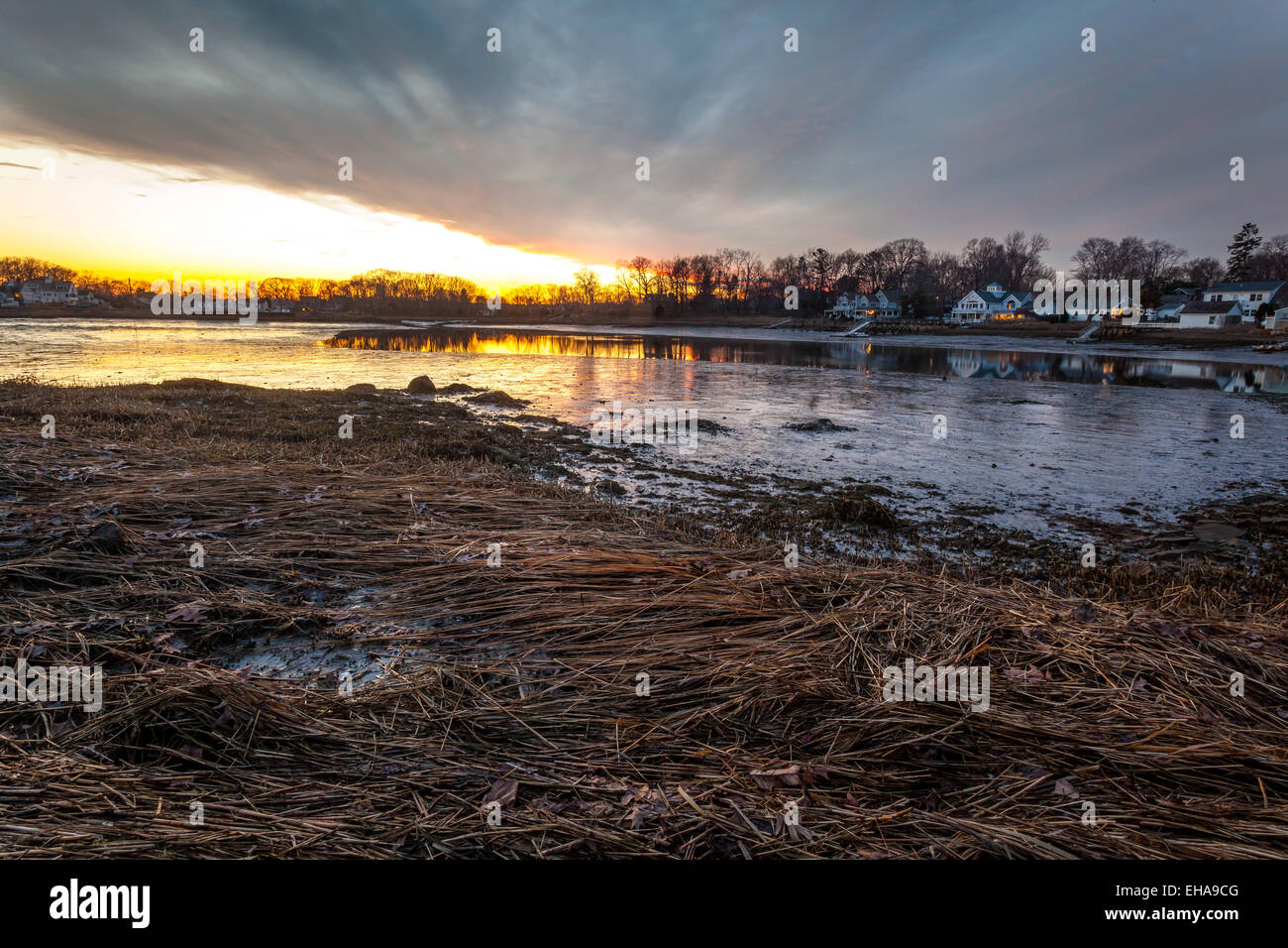 An orange sunset over grassy and muddy waters at low tide. Stock Photo