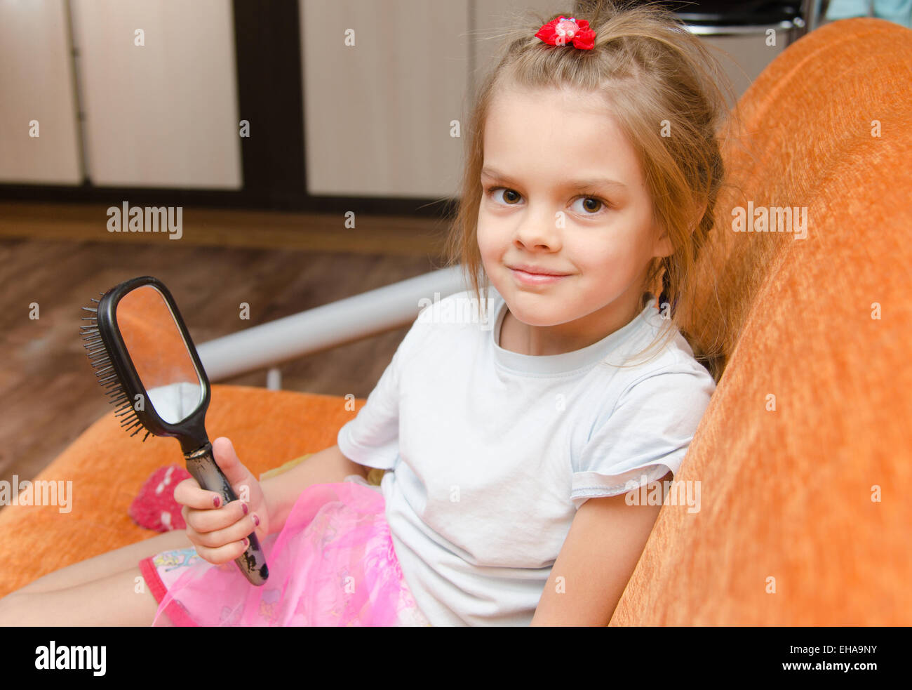Five year old girl sitting on the couch with a mirror in her hand Stock