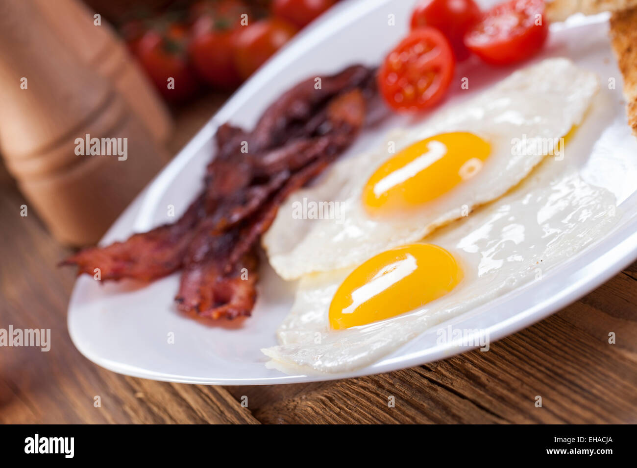 Fried egg and bacon on a plate with spices and vegetables. Studio shot Stock Photo