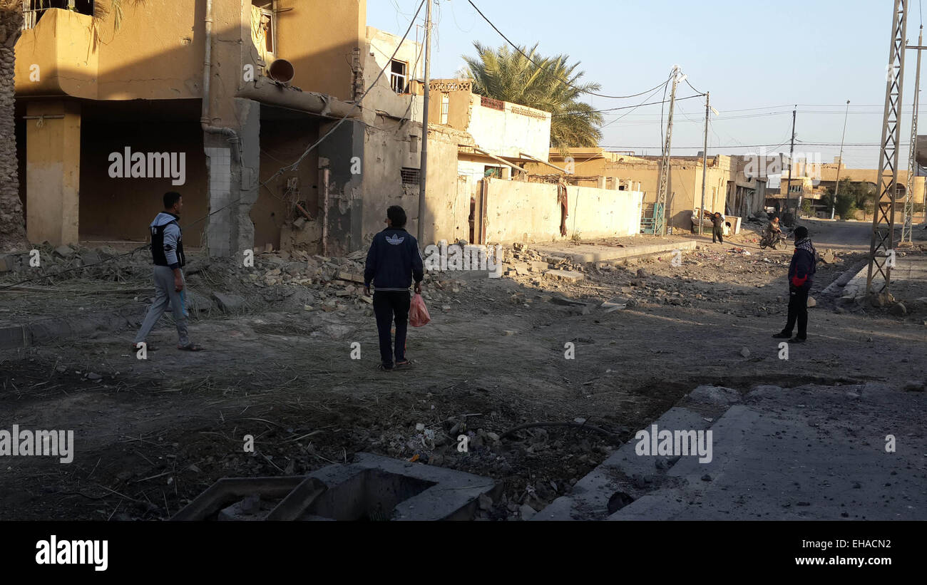Fallujah, Iraq. 10th Mar, 2015. Men walk by destroyed buildings after ...