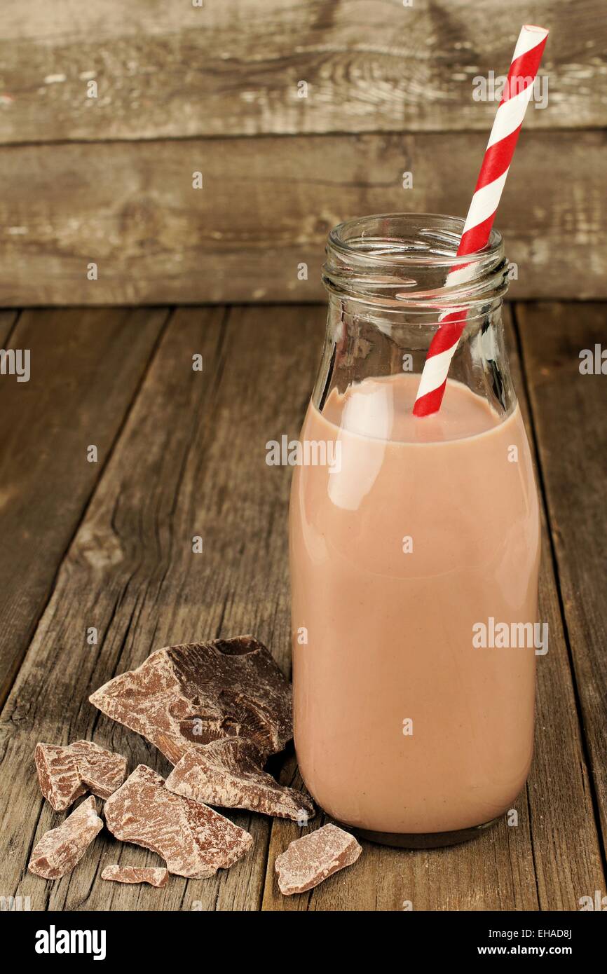 Chocolate milk in traditional bottle with straw on old wood background Stock Photo