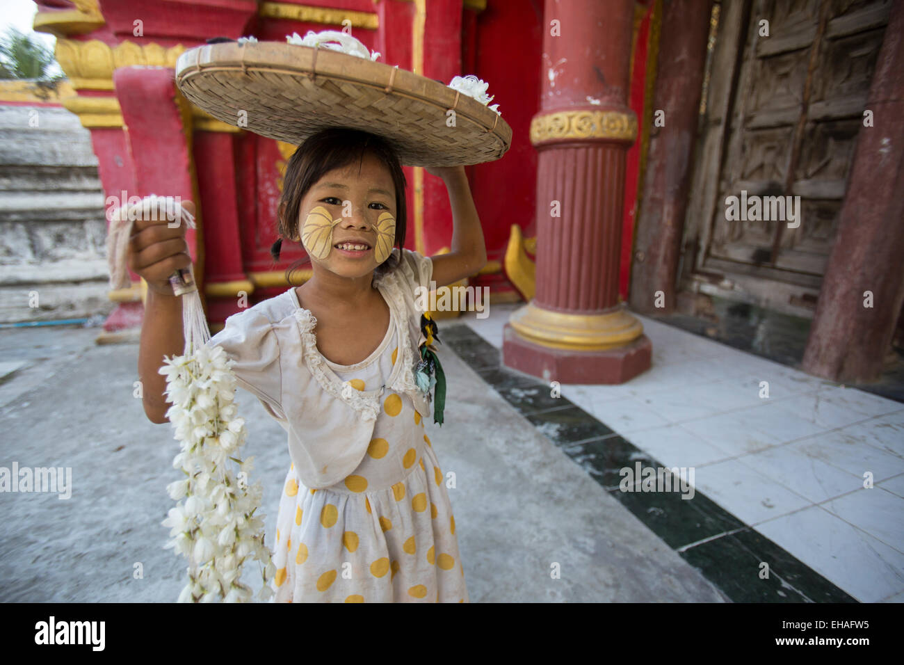 Young girl at Kuthodaw Paya temple in Mandalay, Myanmar, selling flowers for offerings Stock Photo
