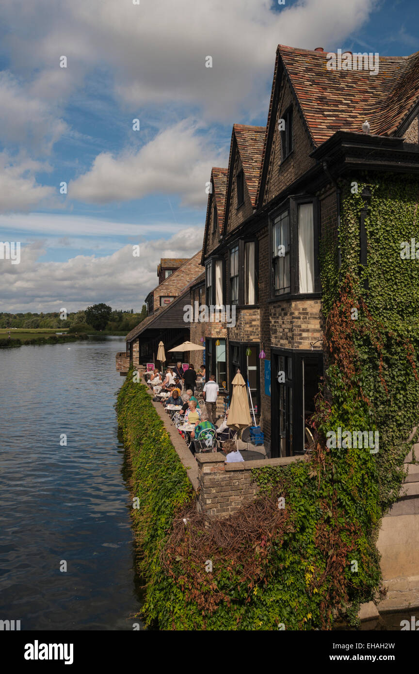 The River Tea Rooms in Saint Ives, Cambridgeshire, from the bridge with people enjoying sunny weather by the River Ouse. Stock Photo