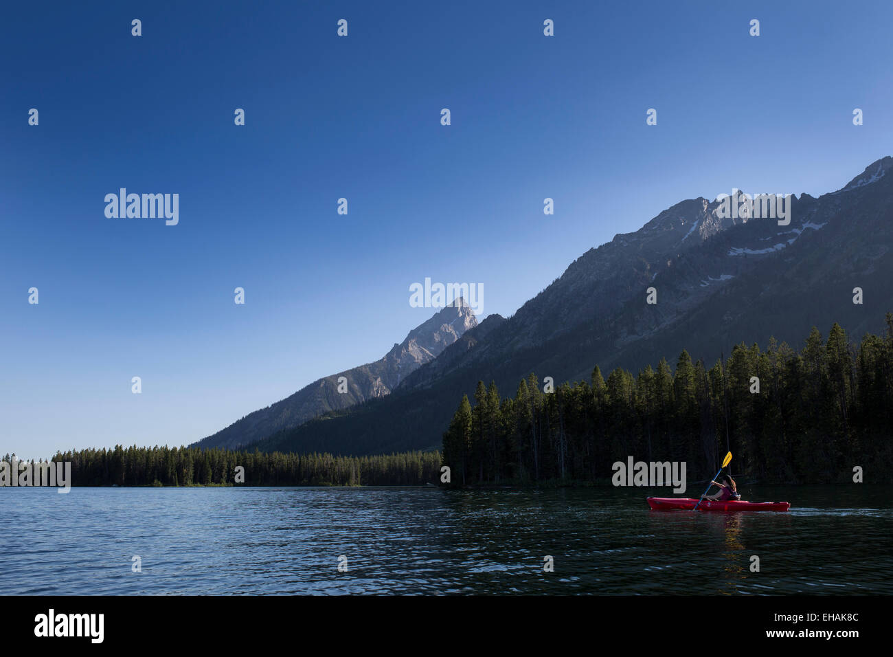 A woman kayaking in Leigh Lake in Grand Teton National Park, Wyoming, with the Teton Range in the background. Stock Photo