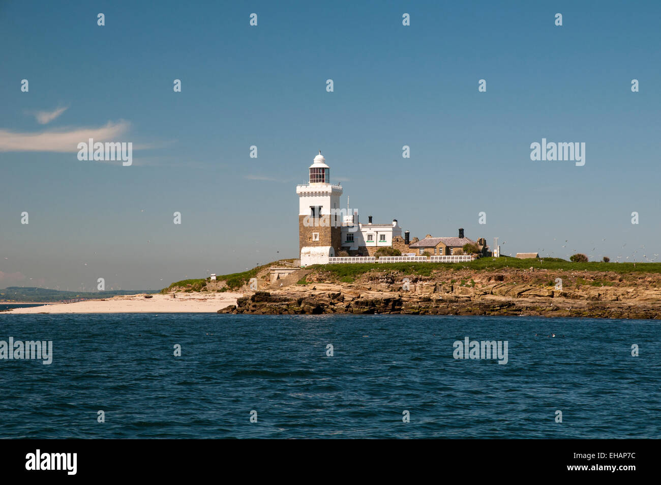 The lighthouse and beach on Coquet Island bird reserve seen from just offshore, Amble Northumberland. June. Stock Photo