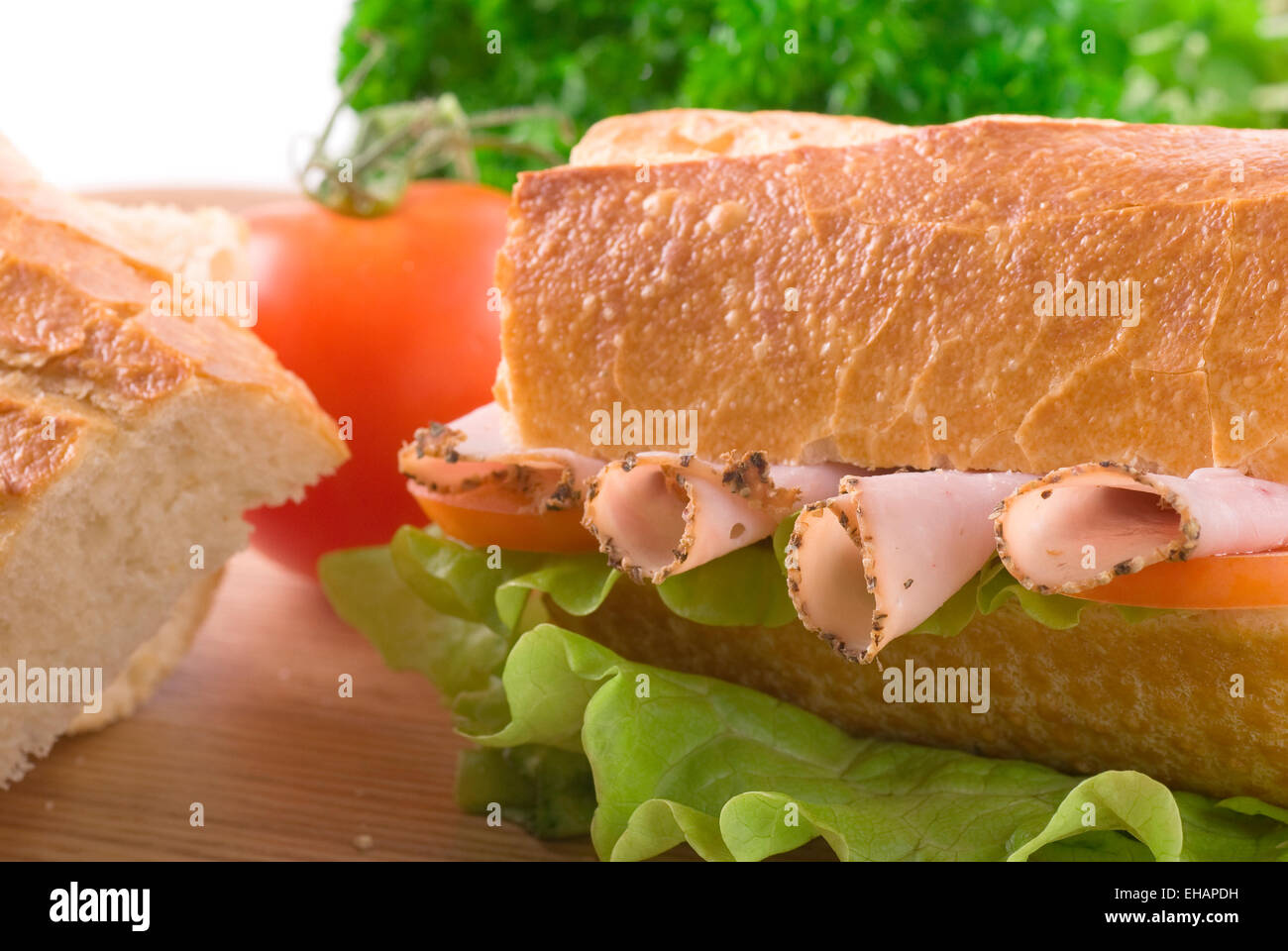 Baguette with pastrami/ham, lettuce and tomato. Stock Photo