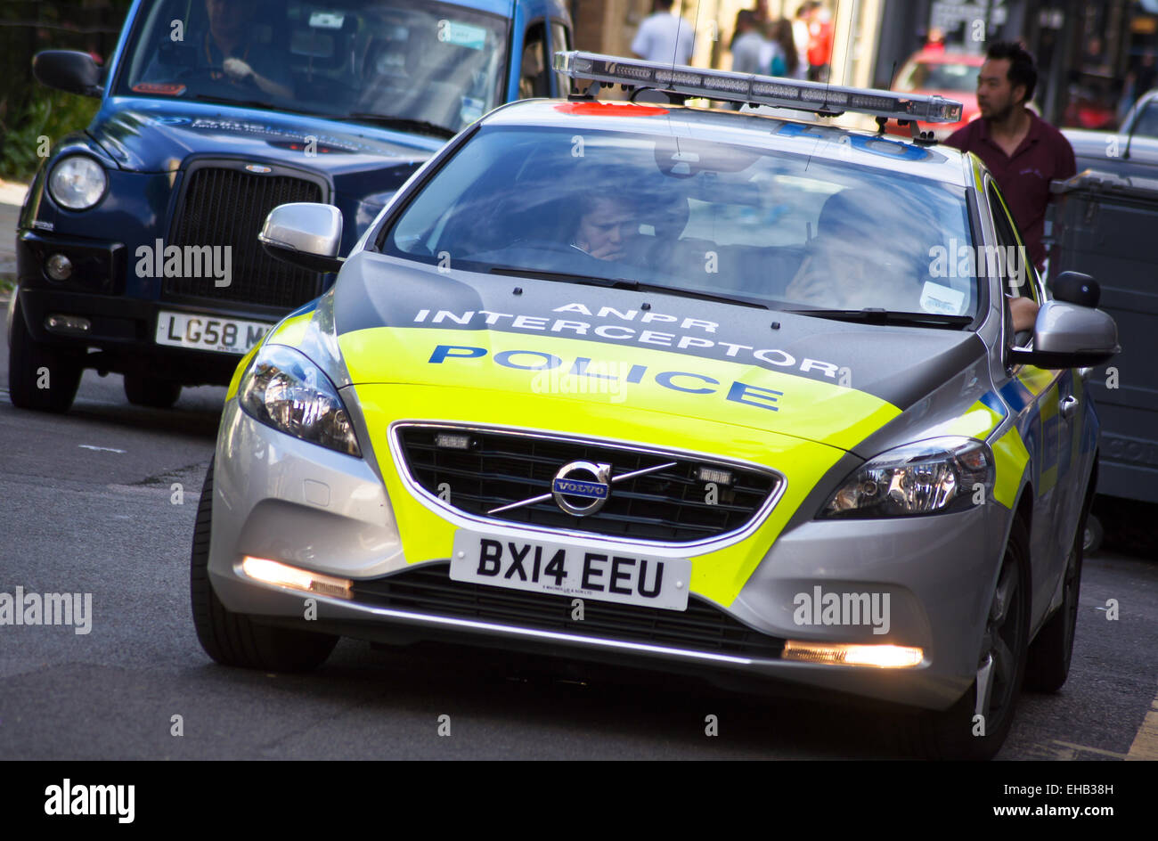 A black cab overtaking an ANPR interceptor Volvo V40 police car, London Stock Photo