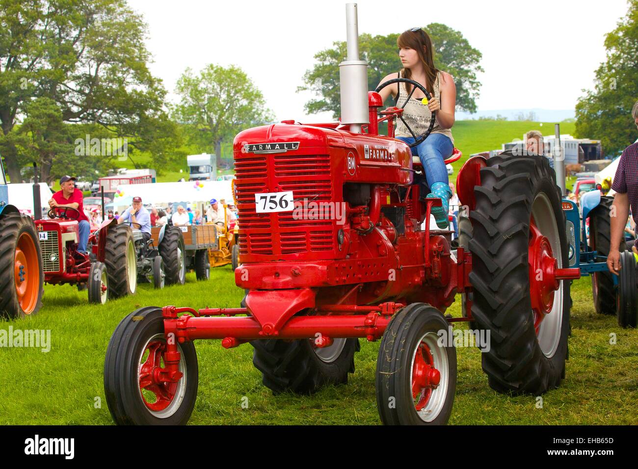 Young woman on McCormick Farmall BM classic tractor. Skelton Show Cumbria, England, UK Stock