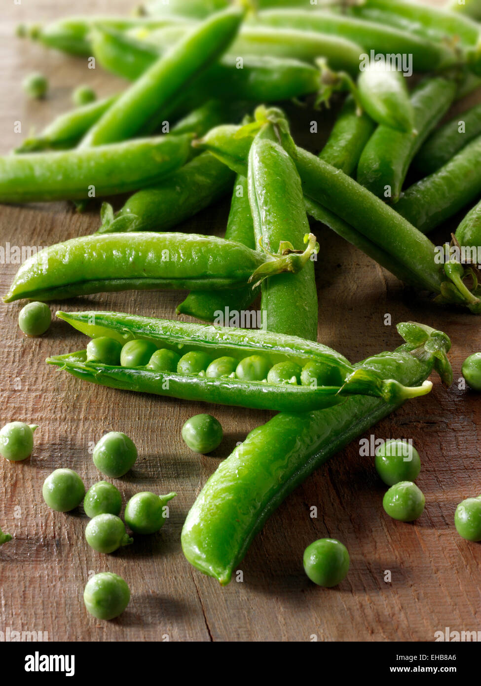 Food still life of fresh picked garden peas and pea in pods on a rustic table in a kitchen being prepared Stock Photo