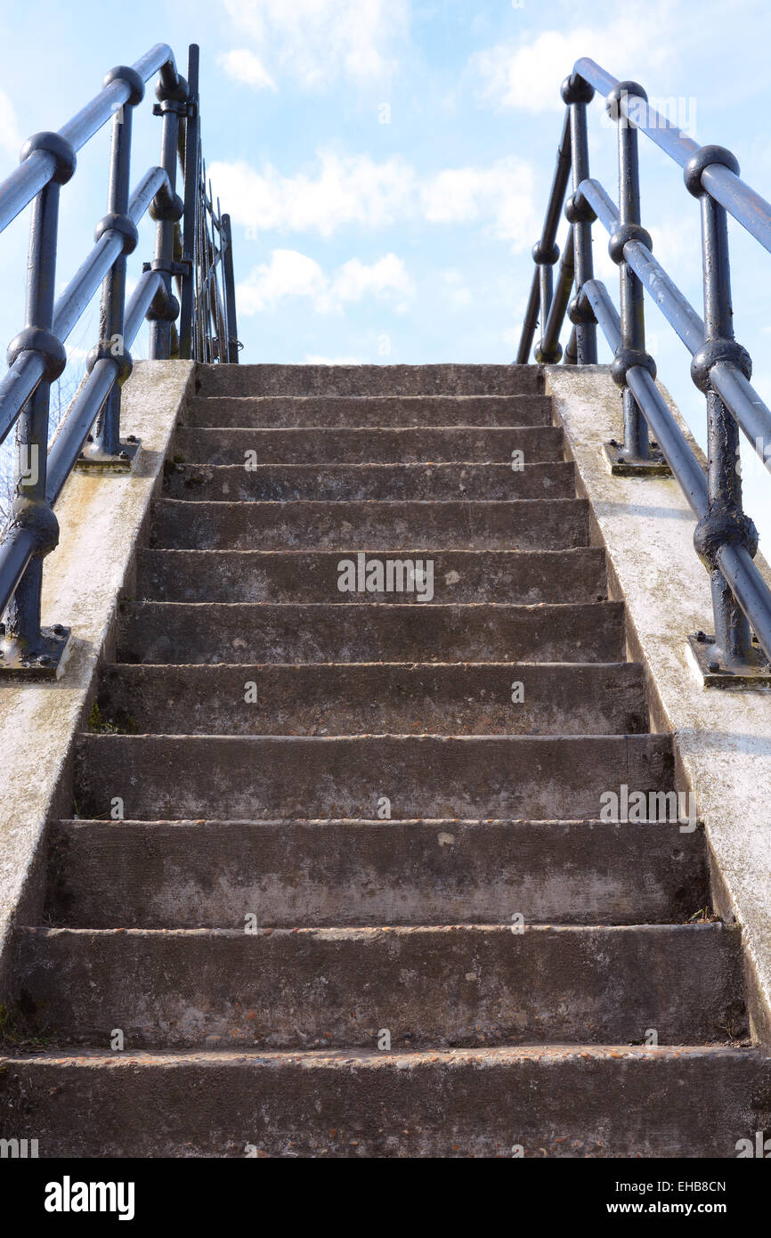 Flight of weathered concrete steps leads upwards into the blue sky Stock Photo