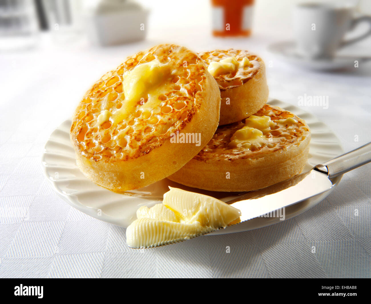 Traditional hot buttered toasted crumpets on a white plate on a table setting, with melted