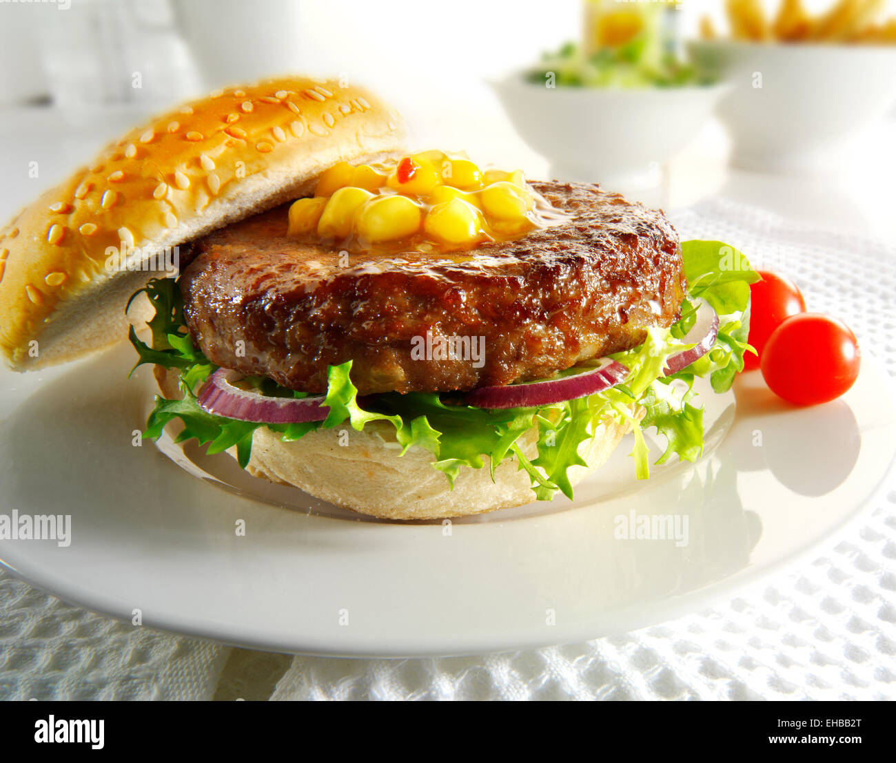 Beef burger with in a bun with salad, fries and sweetcorn relish Stock Photo