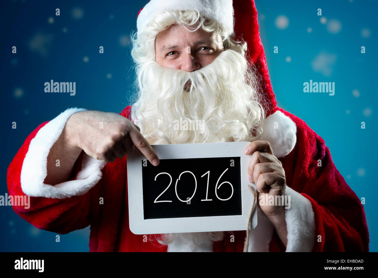 Santa Claus pointing a finger on a blank slate with text 2016 Stock Photo