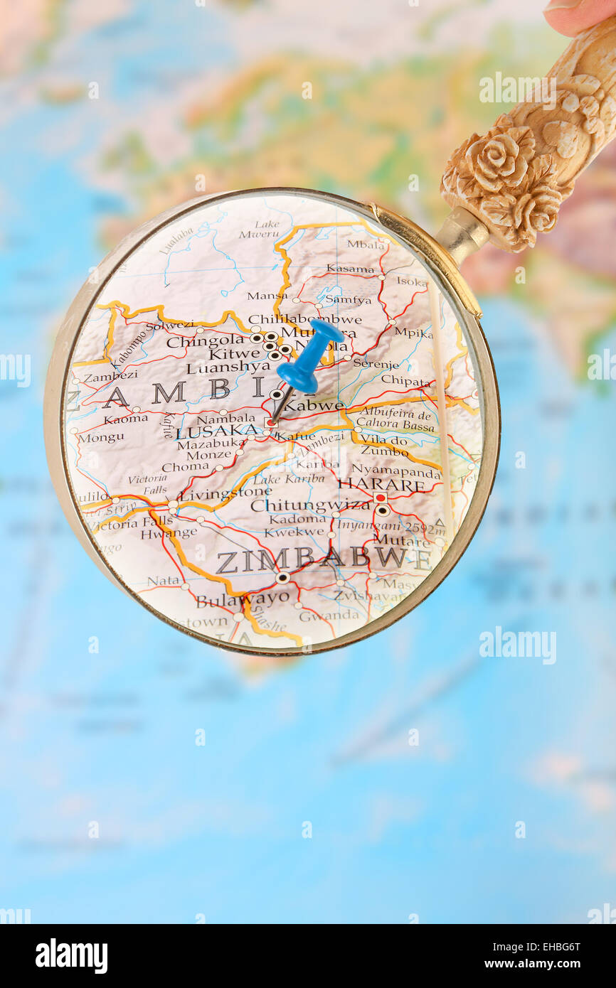 Blue tack on map of Africa with magnifying glass looking in on Lusaka, Zambia Stock Photo