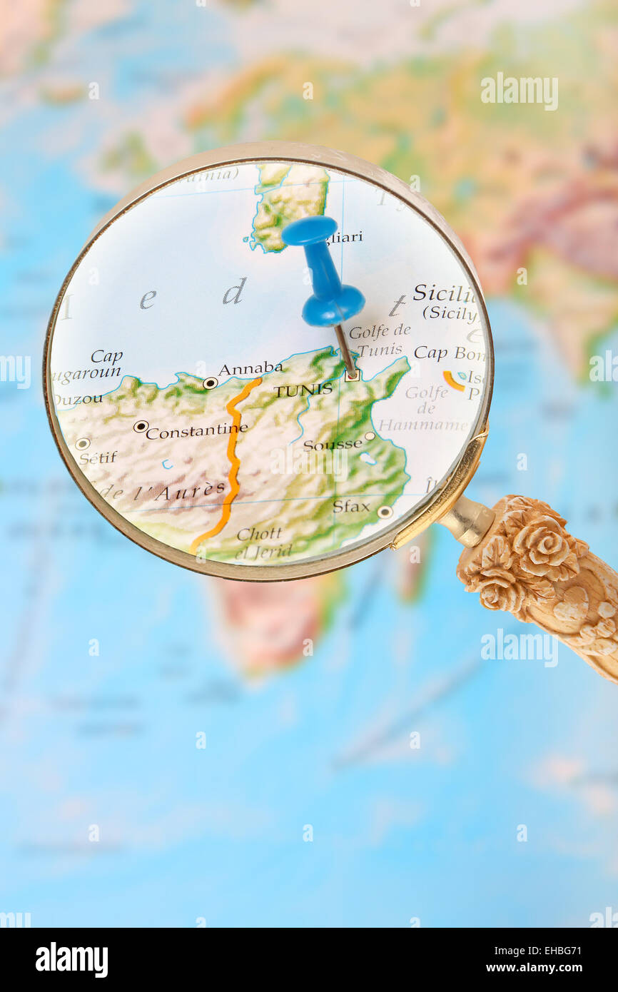 Blue tack on map of Africa with magnifying glass looking in on Tunis, Tunisia Stock Photo