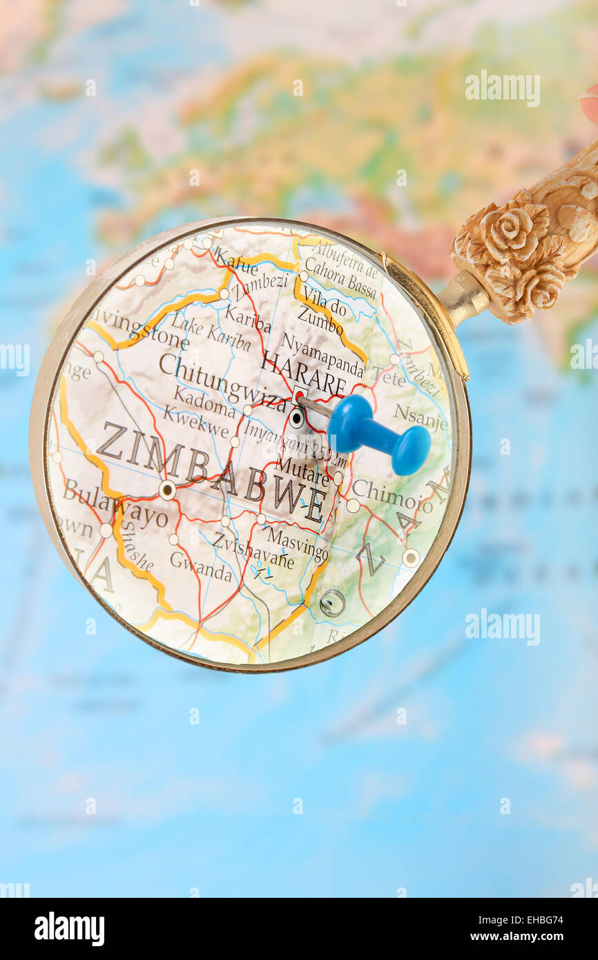 Blue tack on map of Africa with magnifying glass looking in on Harare, Zimbabwe, Stock Photo