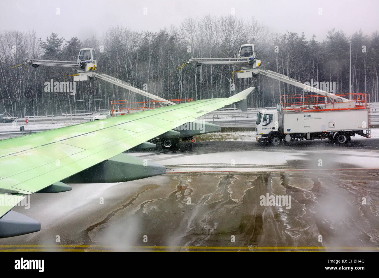 Deicing vehicles at Frankfurt Airport viewed from inside a plane preparing to depart. Stock Photo