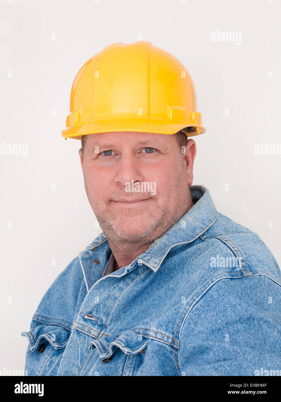 Workman wearing hardhat and jean jacket. White background. Stock Photo