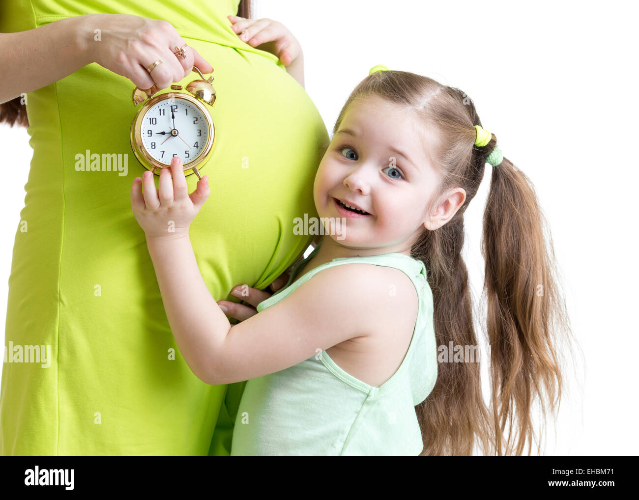 child looks at alarm clock and pregnant woman belly Stock Photo