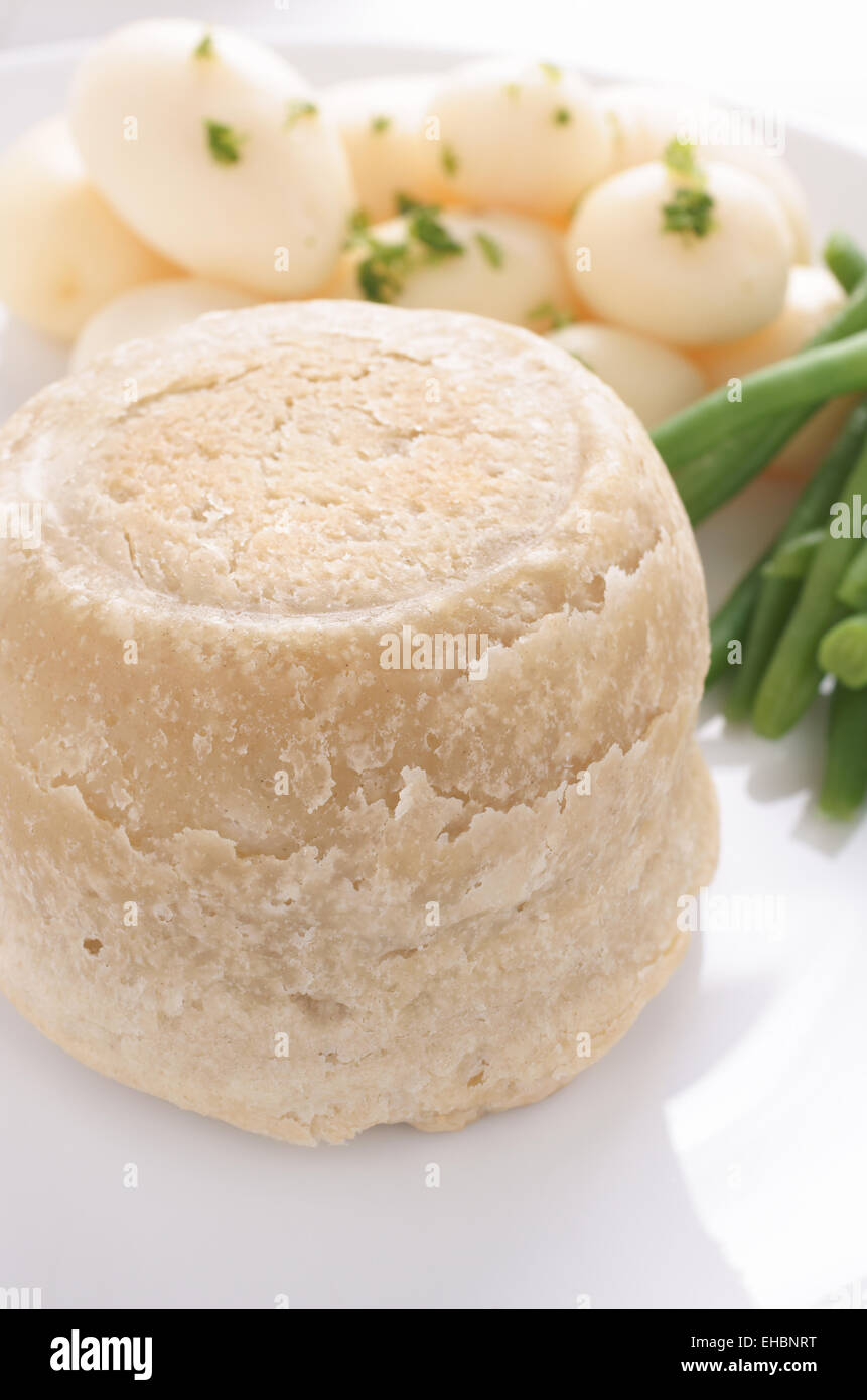 Steak and kidney pudding a traditional steamed suet pastry pie served with new potatoes and
