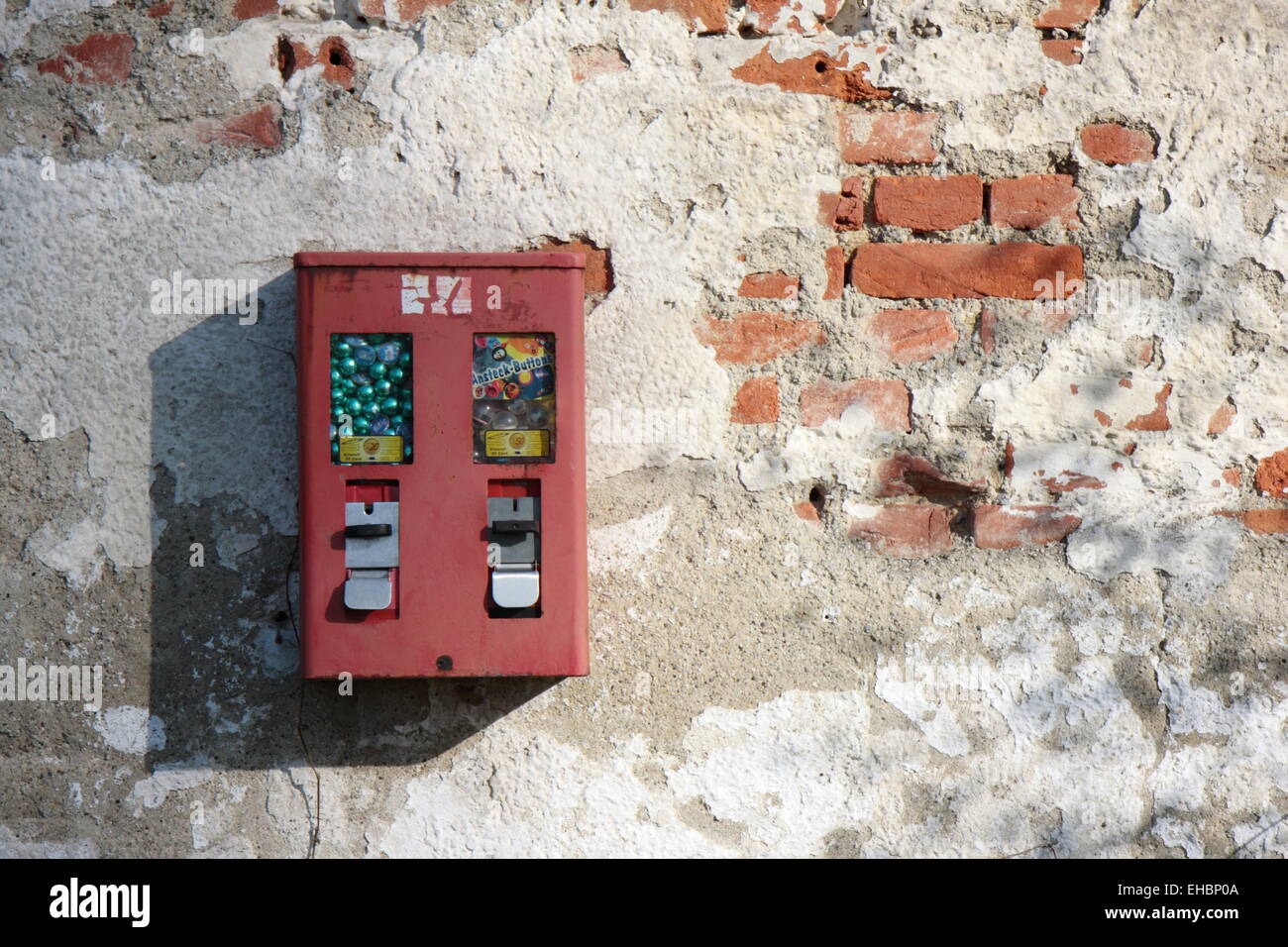a chewing gum dispenser on a battered wall Stock Photo