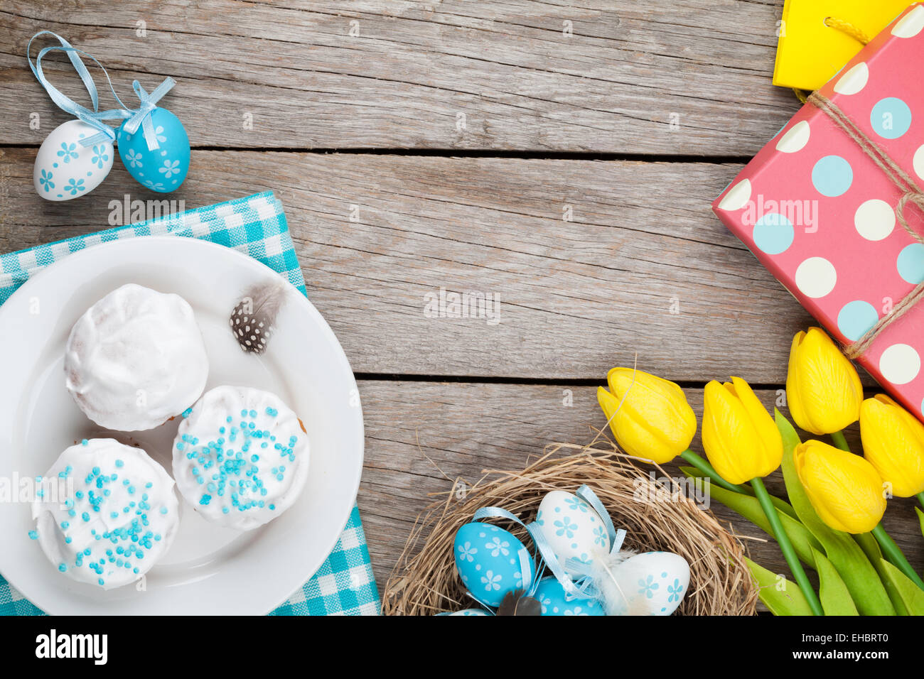 Easter background with blue and white eggs in nest, yellow tulips and ...