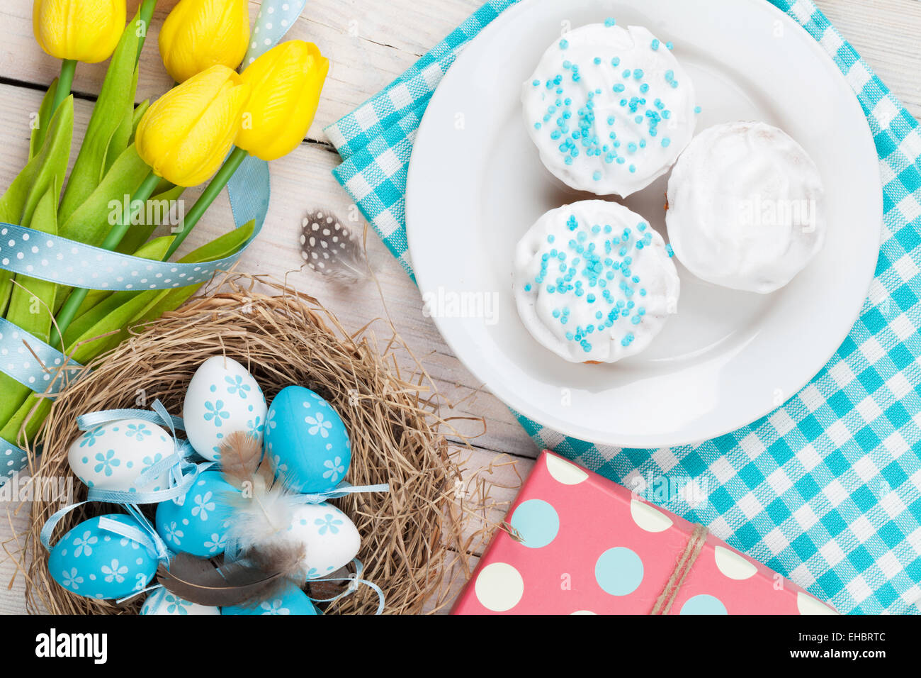 Easter background with blue and white eggs in nest, yellow tulips and ...