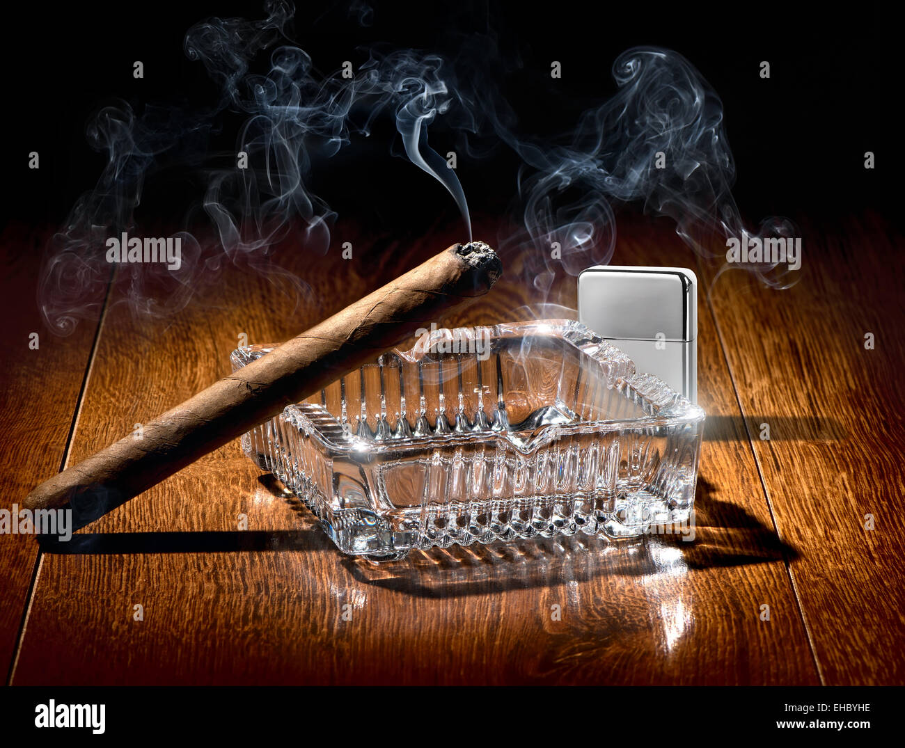 Cigar on ashtray and silver lighter on a wooden table Stock Photo