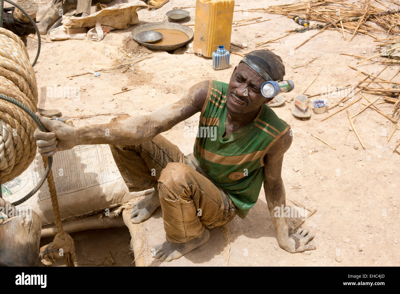 KOMOBANGAU, NIGER, : A miner wearing his head torch beside the vertical entrance shaft of their crude gold mine. Stock Photo