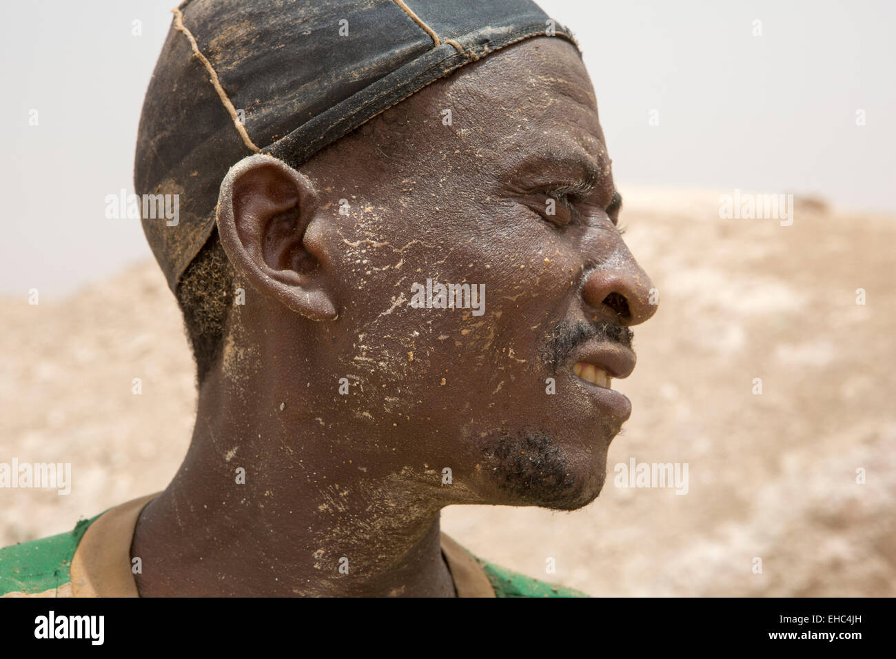 KOMOBANGAU, NIGER, : A miner wearing his head torch beside the vertical entrance shaft of their crude gold mine. Stock Photo
