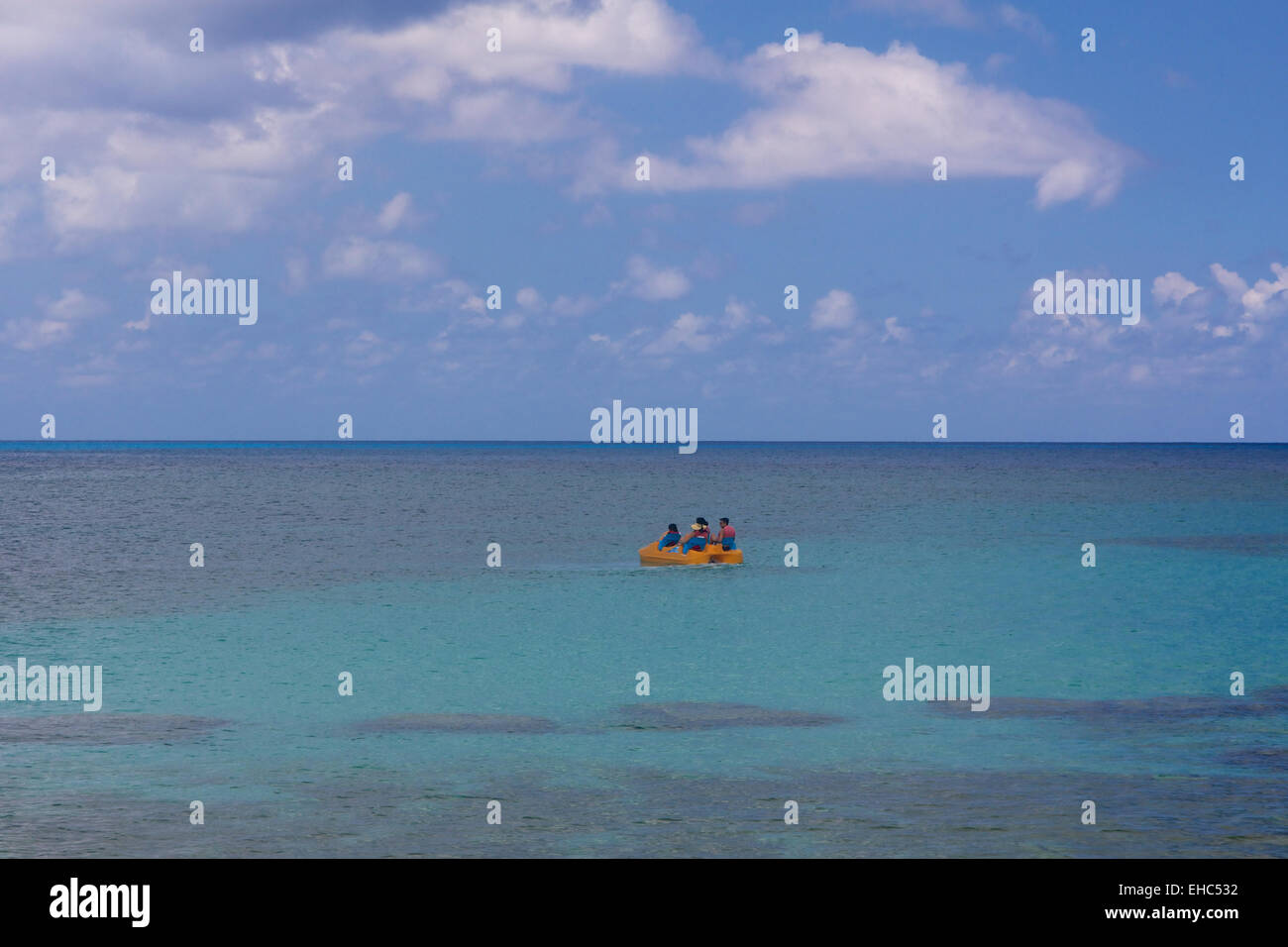 Tiny yellow paddle boat in the vast Caribbean Sea. Stock Photo