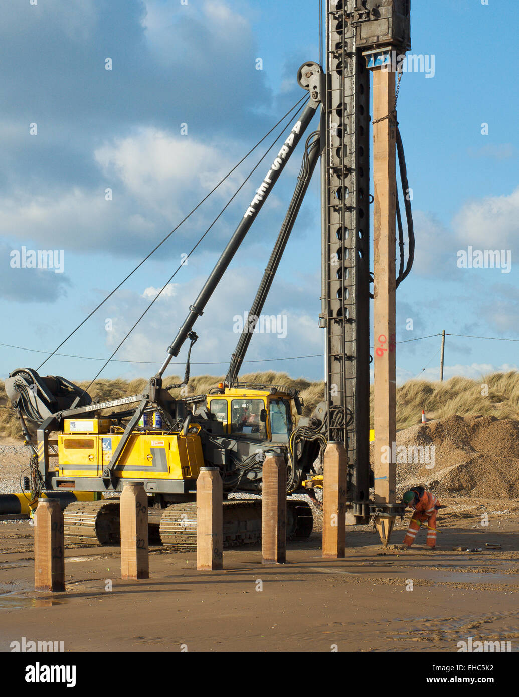 Pile driver at work, driving timber groynes into Camber Sands. Stock Photo