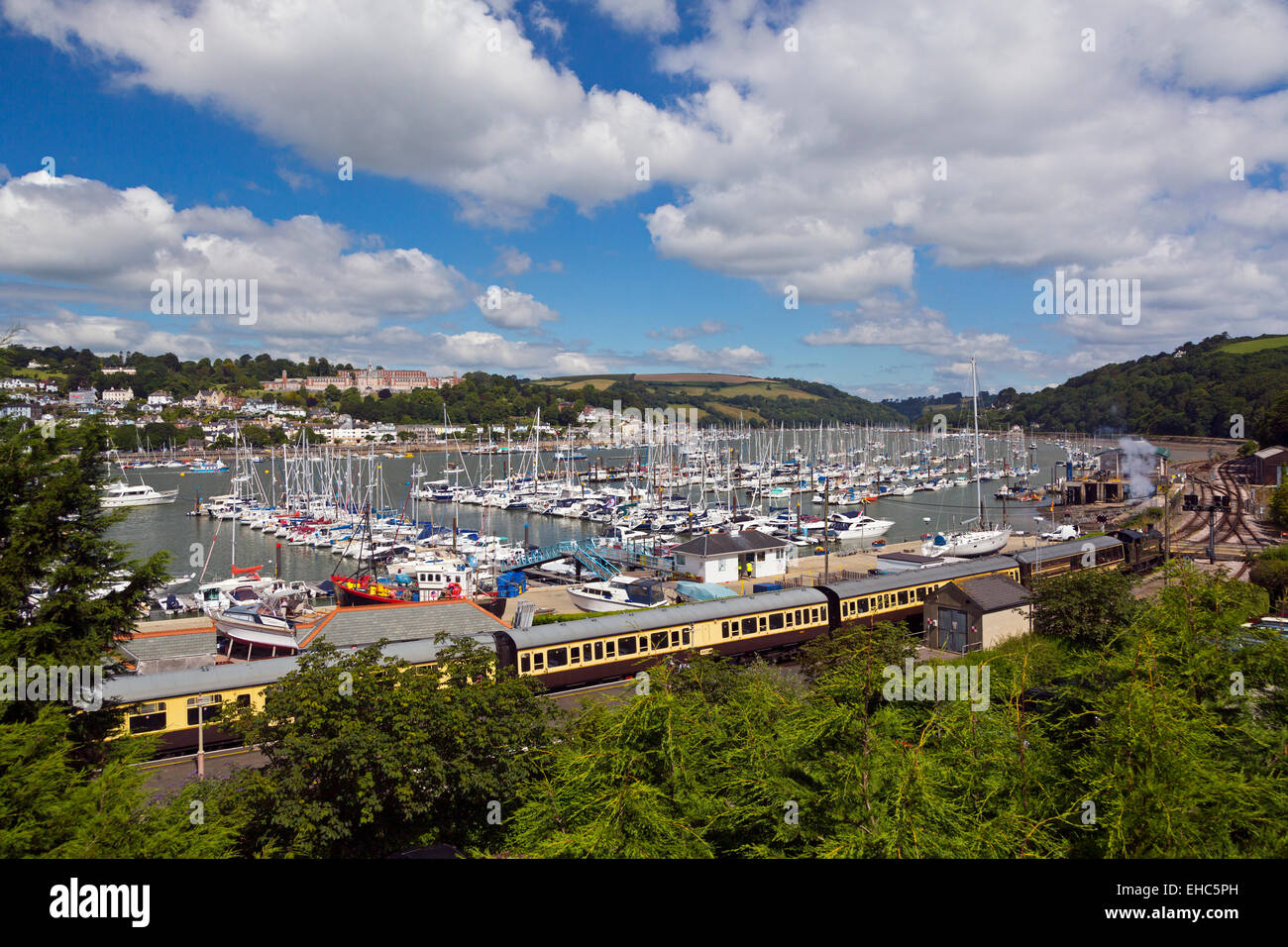 The Kingswear to Paignton steam train and coaches at Kingswear Station platform, yacht marina beyond and Dartmouth in distance Stock Photo