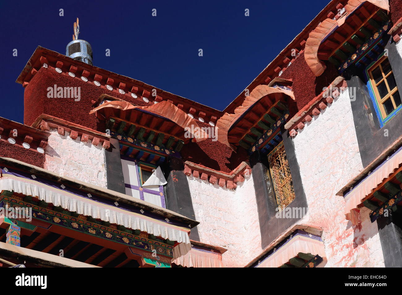 Colorist wooden windows under fabric edgings-dhvaja or victory banner on roof-white washed walls of the Drepung-Rice Heap monast Stock Photo