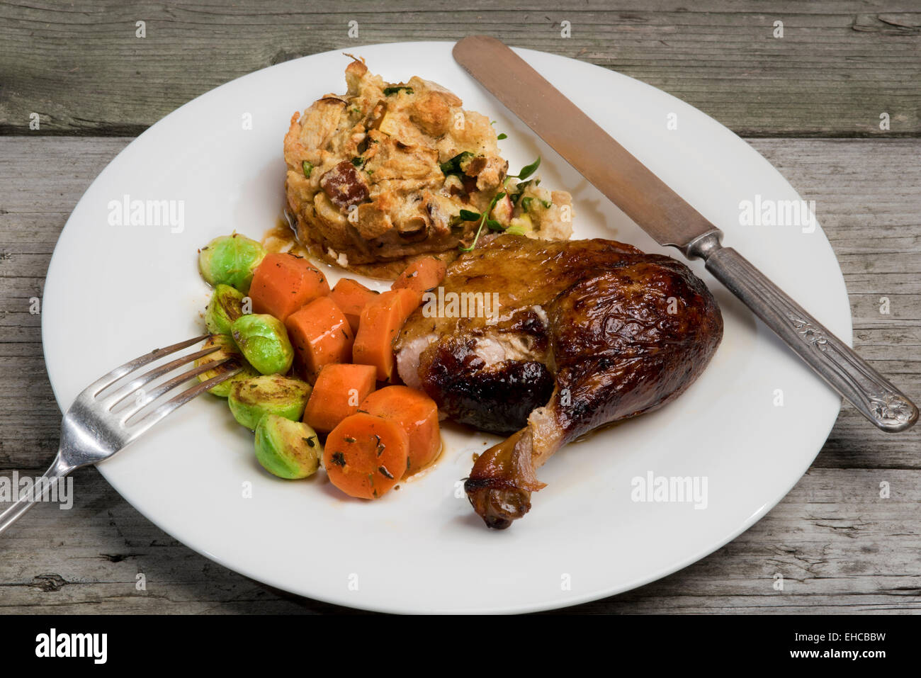 Roasted duck leg with apple and herb stuffing, carrots and Brussels