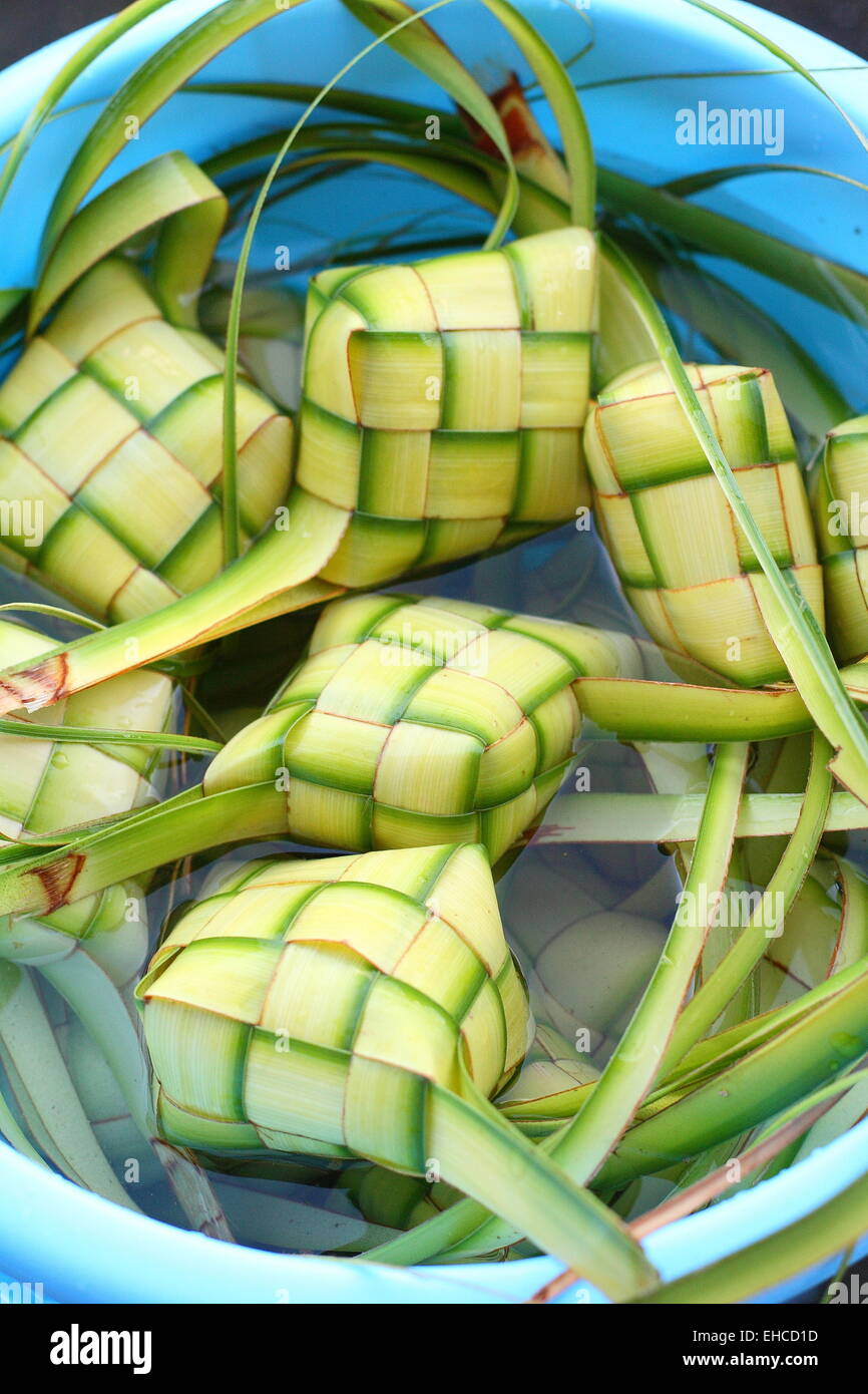 Freshly woven ketupat soaking in a bucket of water to retain its freshness Stock Photo