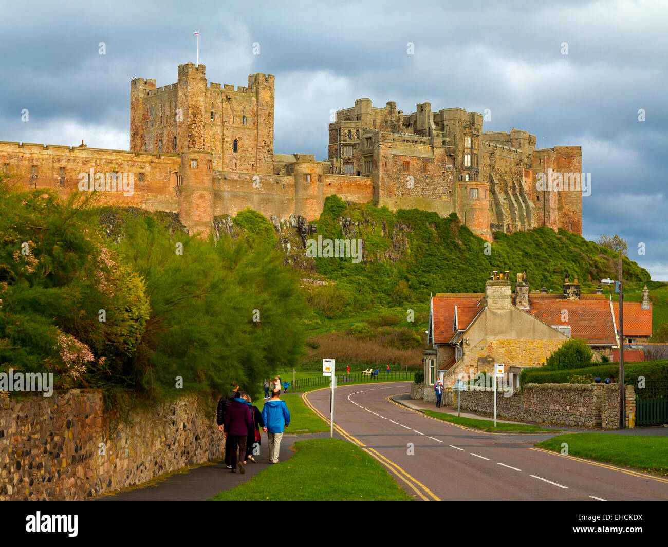 Tourists walking on the road below Bamburgh Castle in Northumberland