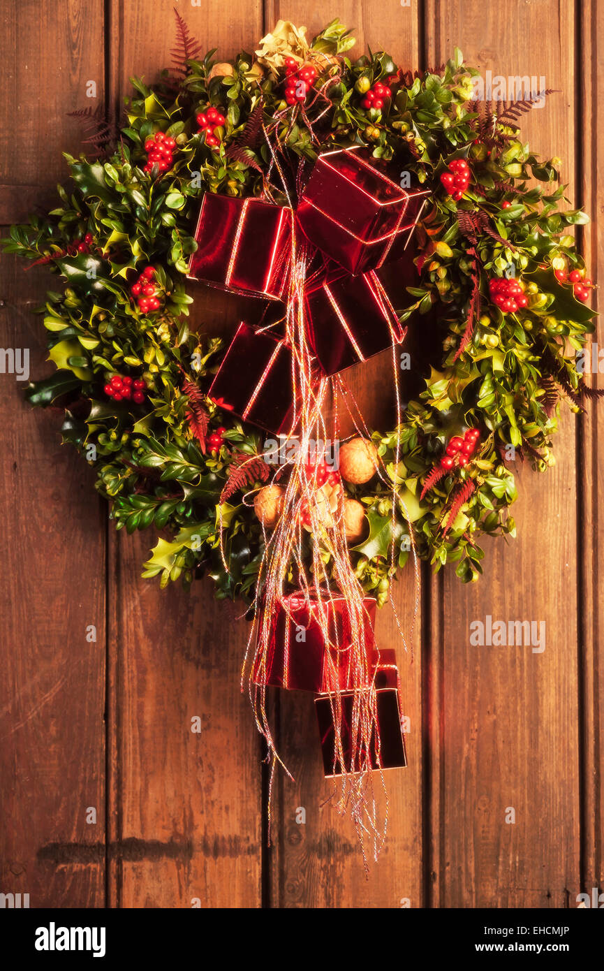 Holly wreath with red packets, on a wooden door Stock Photo