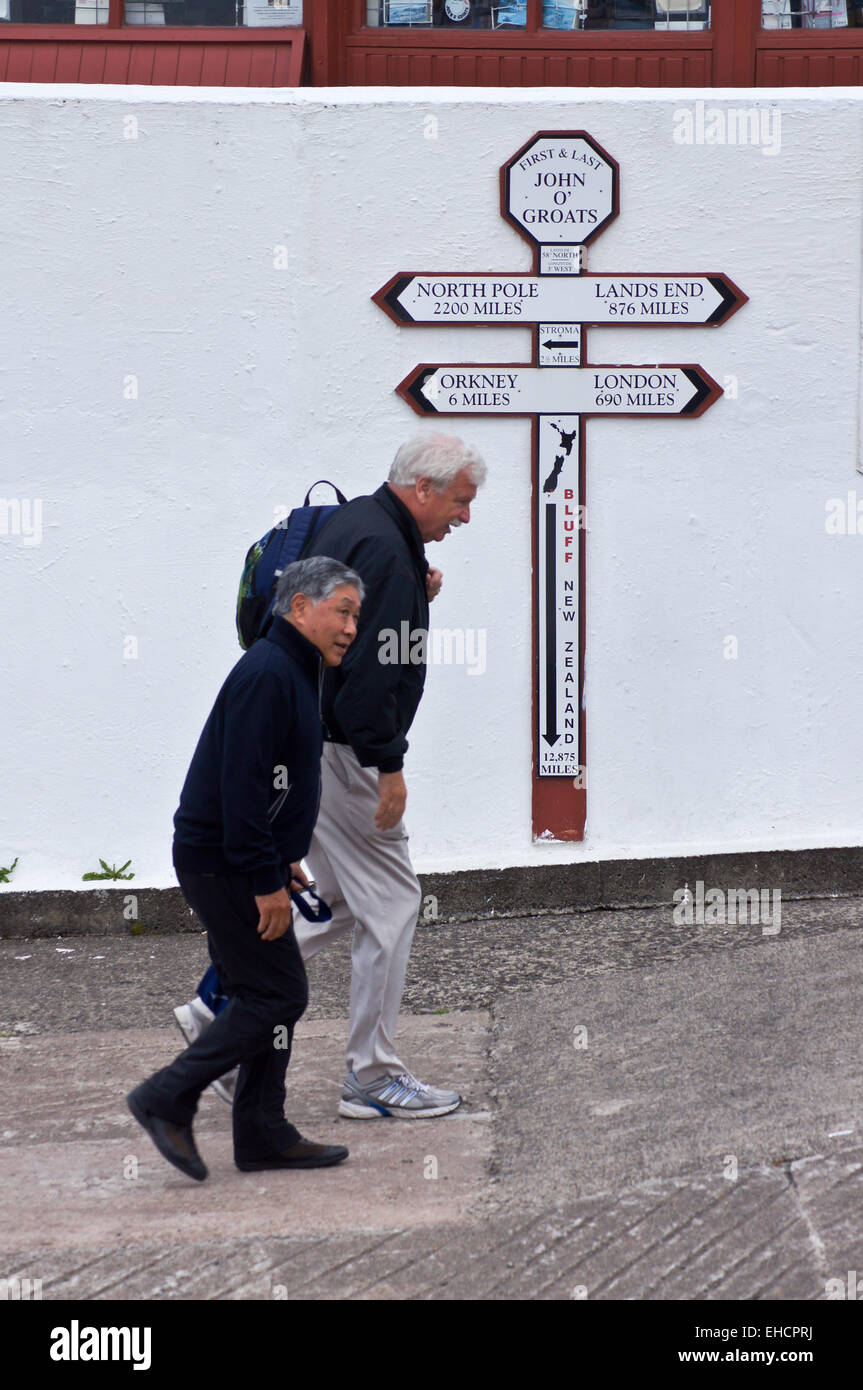 Walkers passing the sign showing distances to Land's End, John O'Groats, Caithness, Scotland Stock Photo